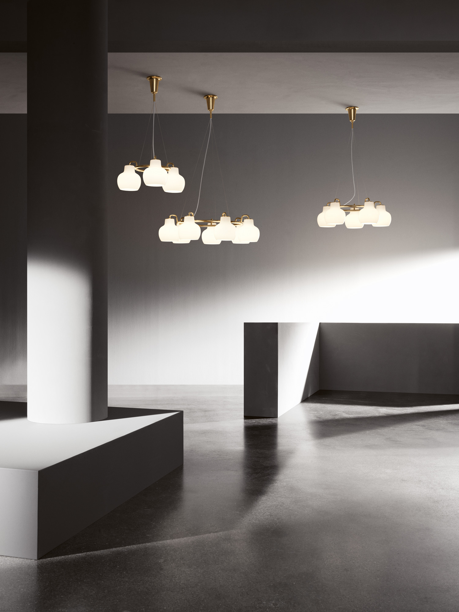 Drei Louis Poulsen VL Ring Crown Pendelleuchten mit goldenem Rahmen und weißen Glaslampen in modernem Raum.