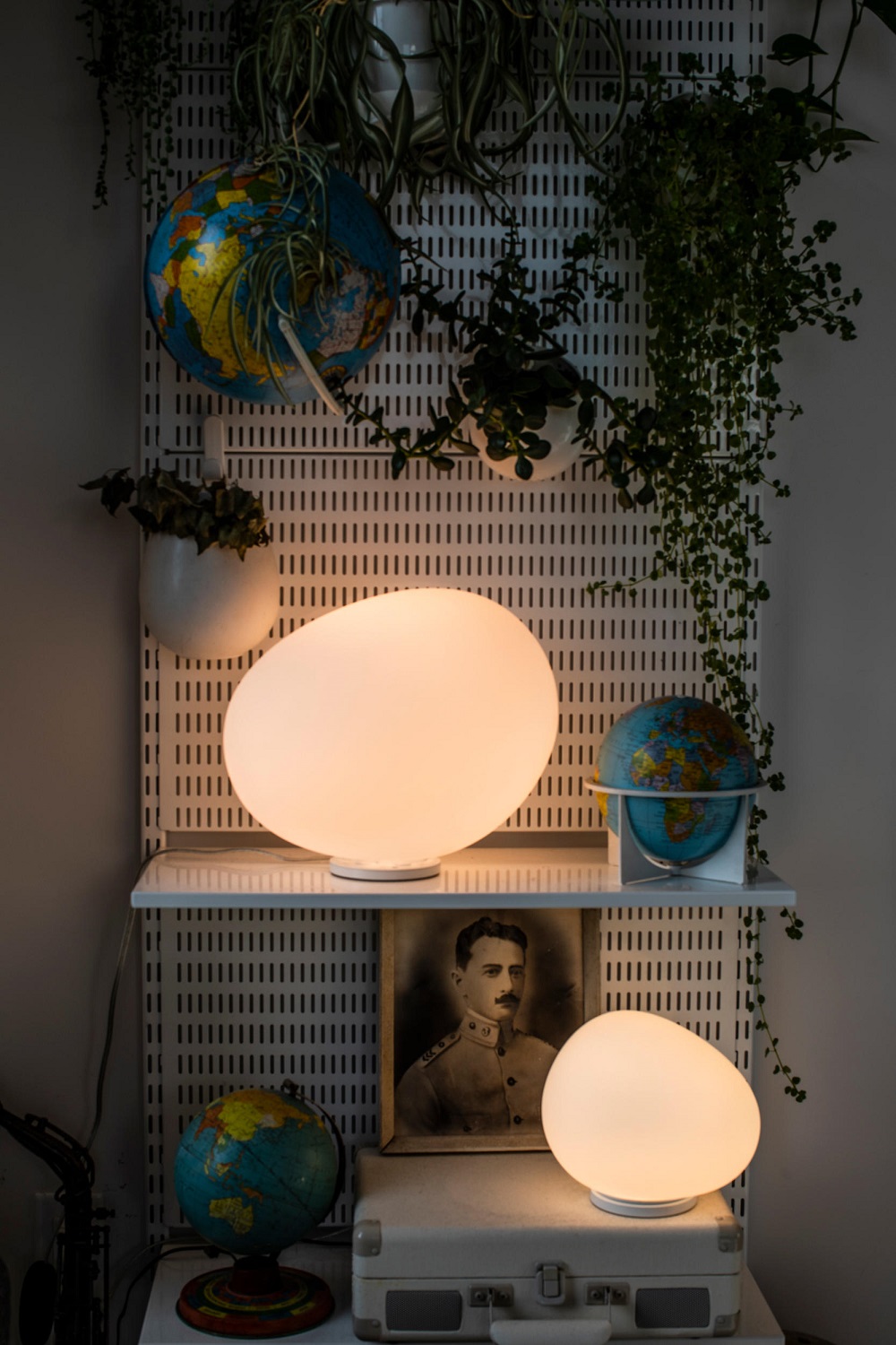 Gregg Tischleuchte von Foscarini: Zwei organisch geformte, leuchtende Lampen auf Regal mit Dekoration.