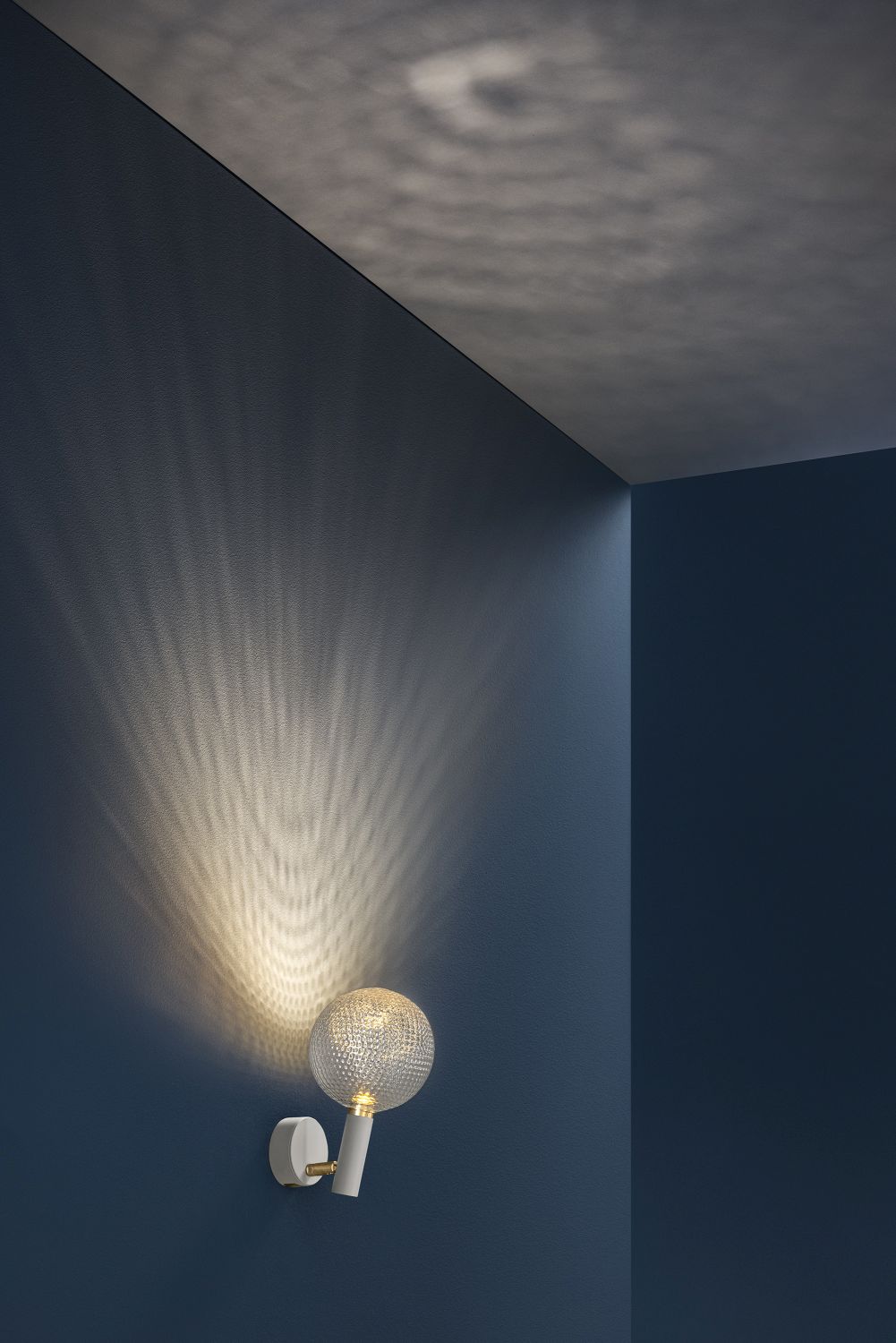 Par Wandleuchte von Catellani & Smith: Runde Designleuchte mit besonderem Lichteffekt an blauer Wand.