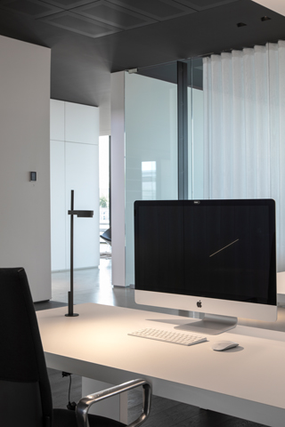 Kido Desk Tischleuchte von Belux, schwarze Ausführung mit fester Befestigung auf einem Schreibtisch.