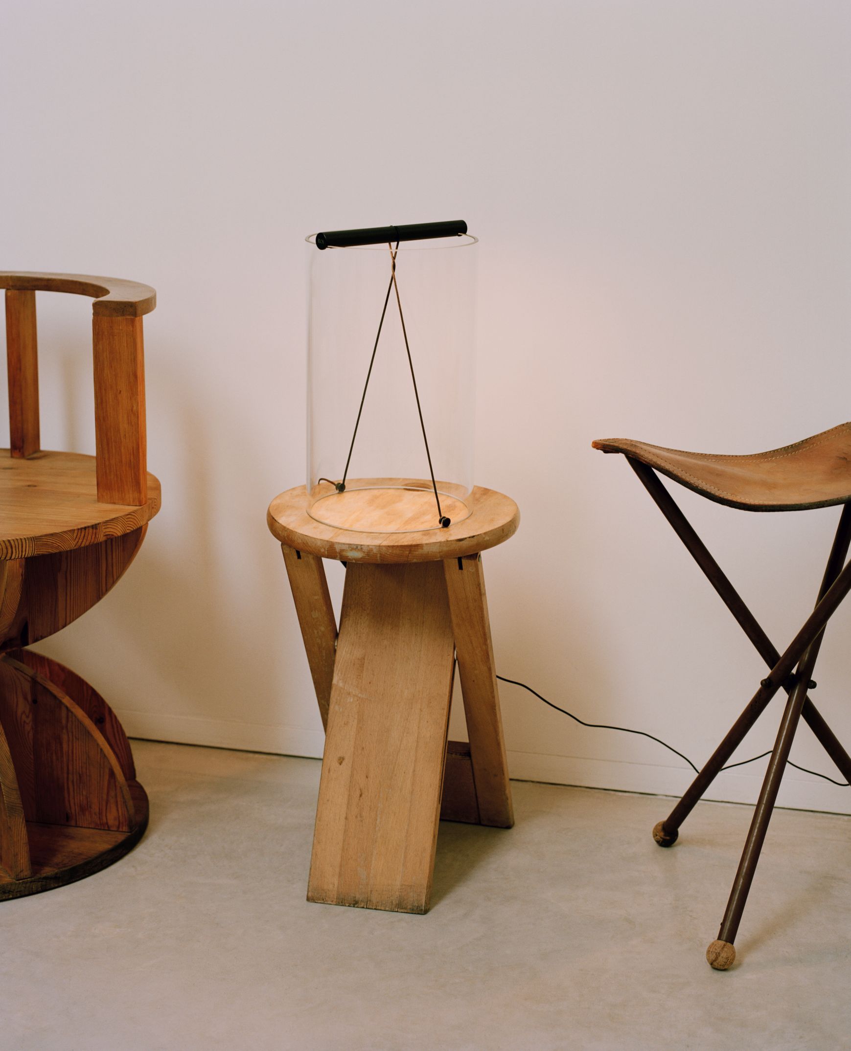 To-Tie T2 LED Tischleuchte in Schwarz eloxiert auf Holzhocker, modernes Designobjekt für Wohnraum.