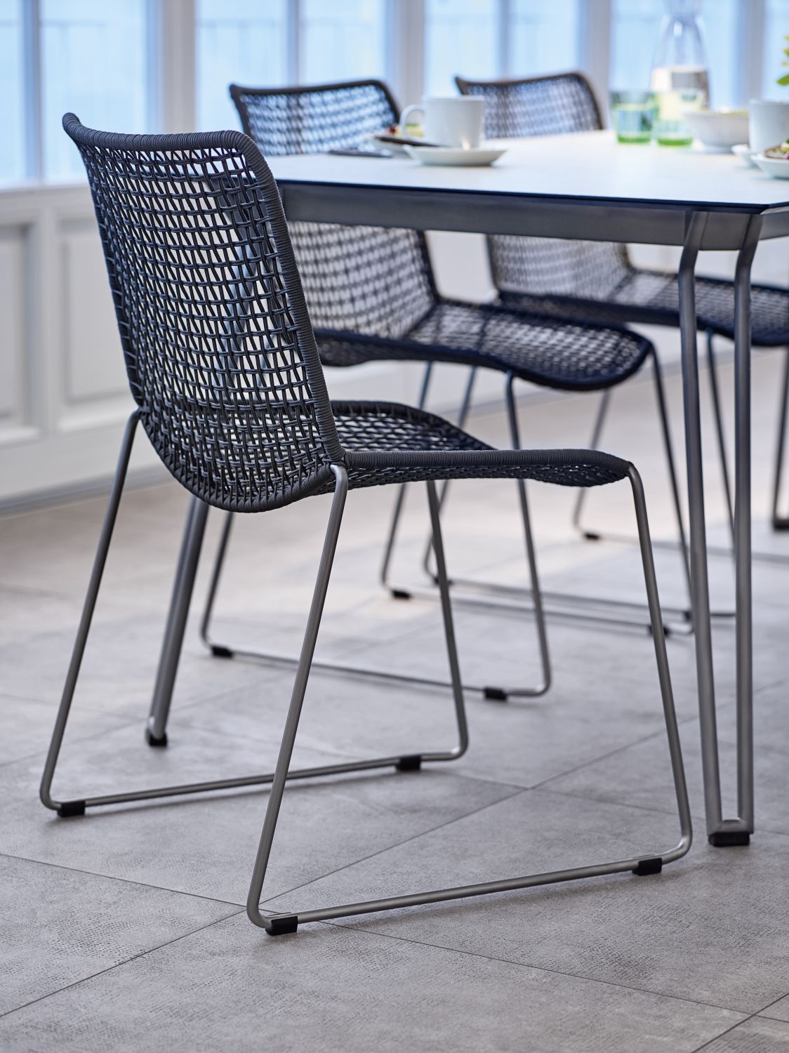 Slope Chair Stuhl von Weishäupl, ein moderner Outdoor-Stuhl mit geflochtener Sitzfläche und Metallgestell.