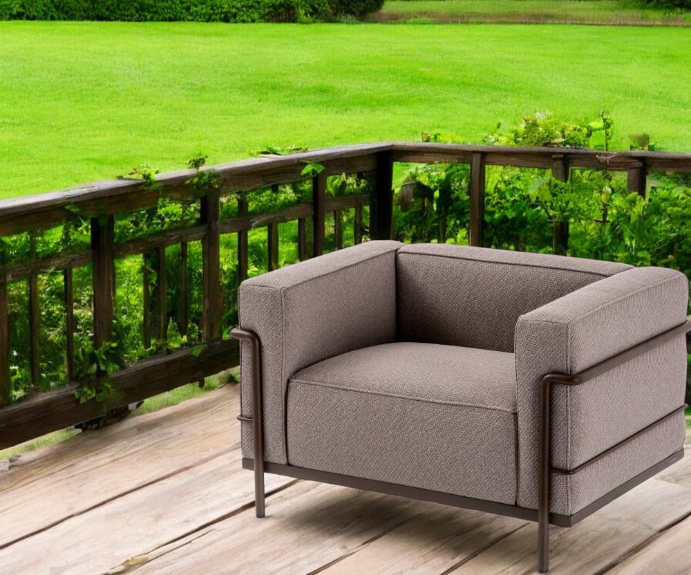 Cassina 3 Fauteuil Grand Confort Sessel für den Außenbereich auf einer Holzterrasse mit Grünfläche.
