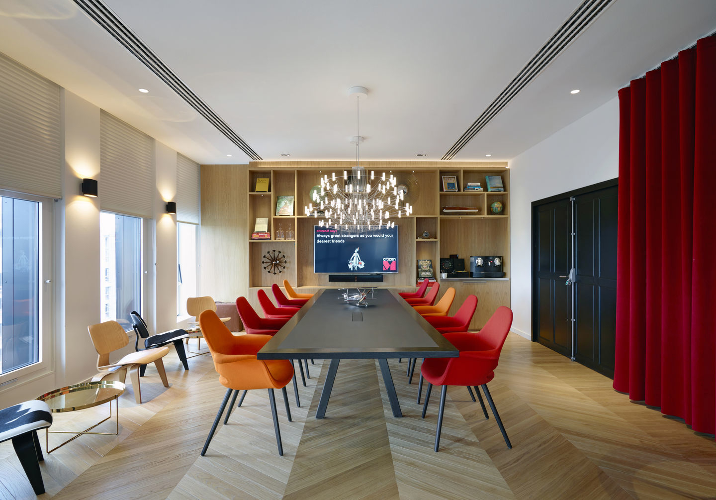 Konferenzraum mit Vitra Plywood Group LCW Stühlen in Rot und Orange am langen Tisch.