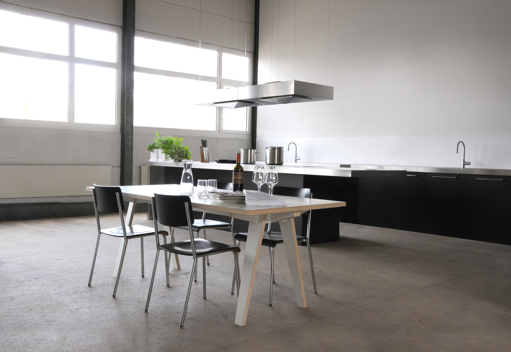 Moderner Tojo Tisch aus Holz mit Stühlen in minimalistischer Küche, gedeckt mit Geschirr.