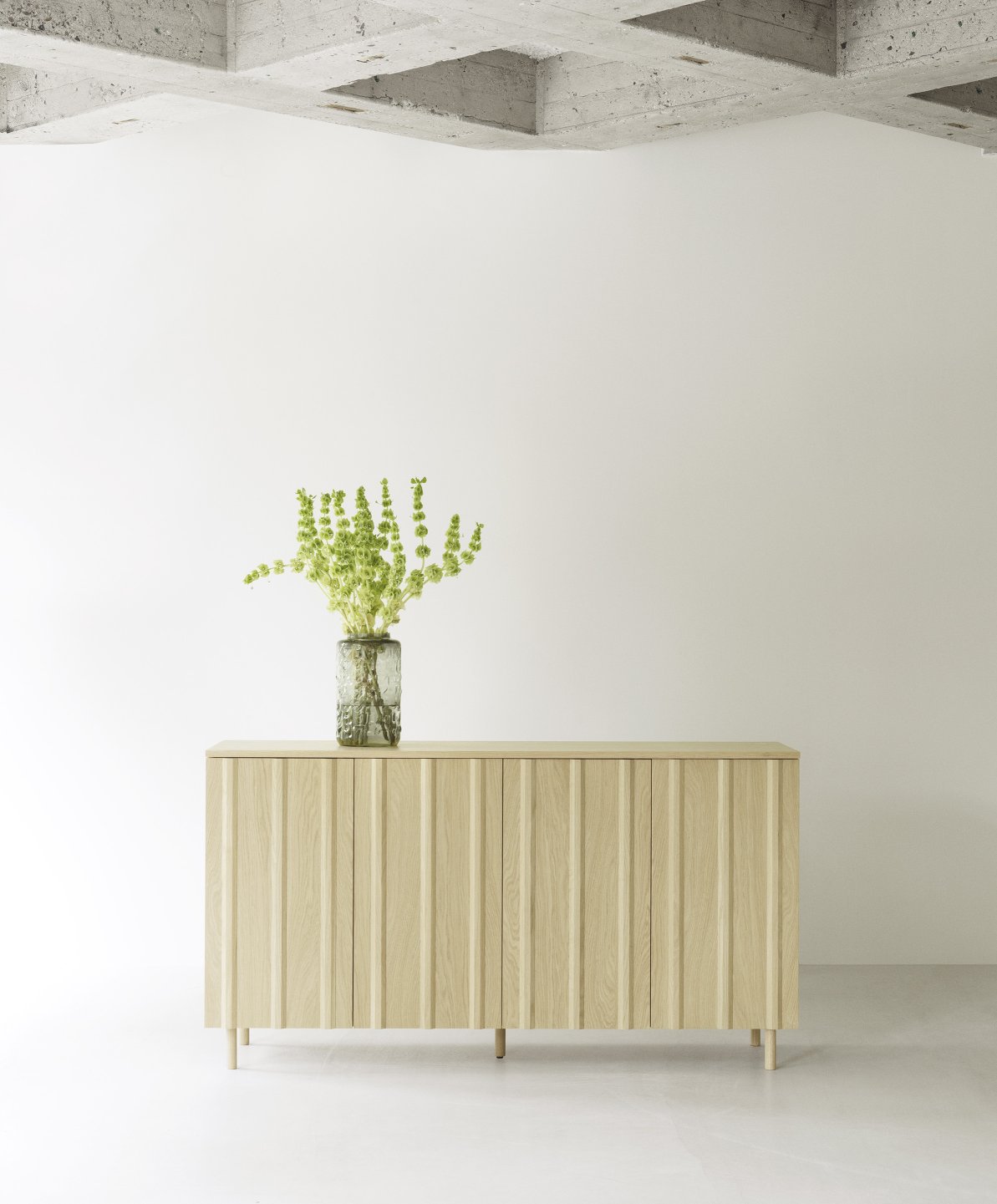 Helles Rib Sideboard von Normann Copenhagen mit geriffelten Türen und Vase mit grünen Blumen.