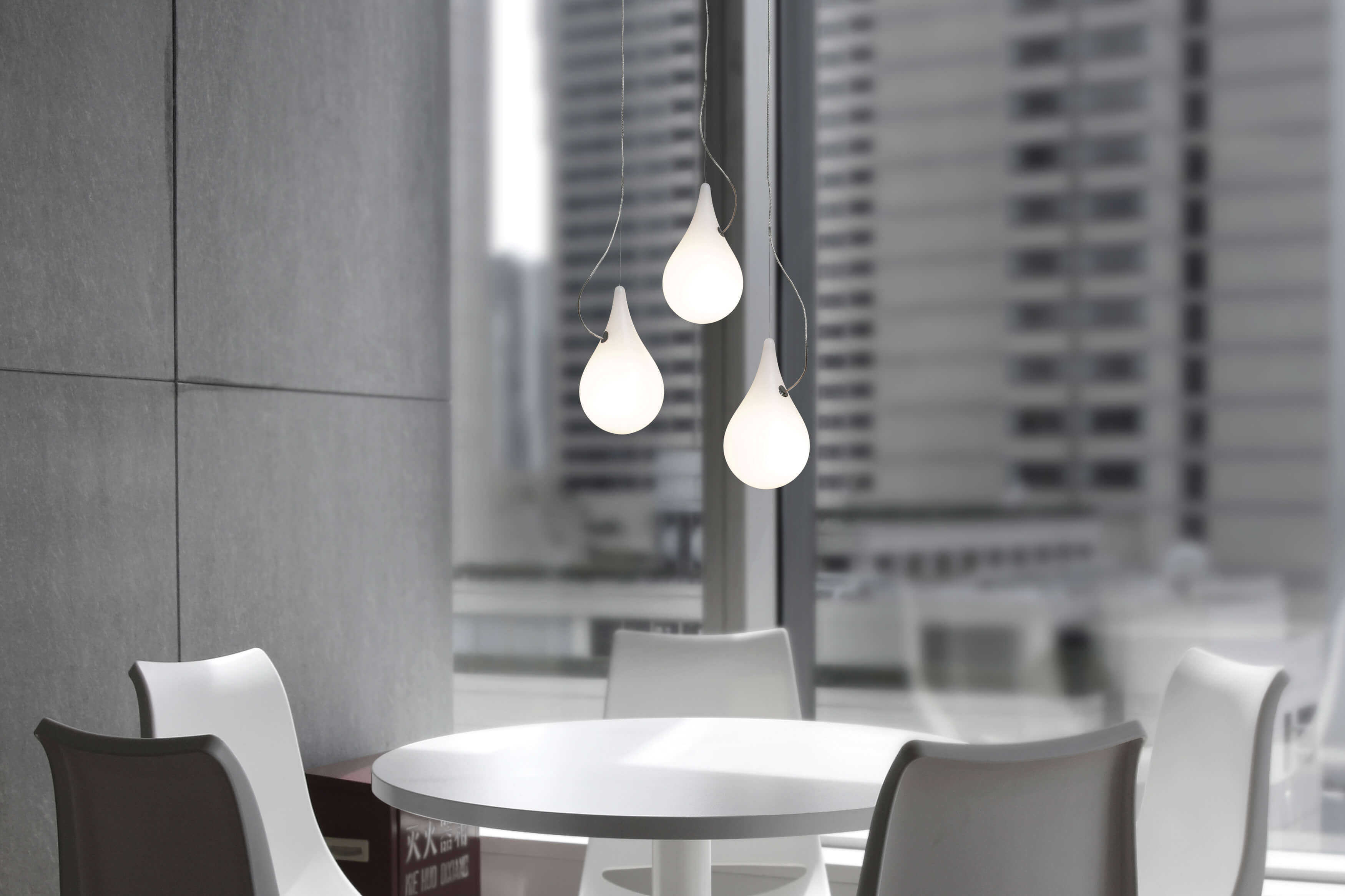 Liquid Light Pendelleuchte: Drei tropfenförmige Lampen über einem weißen Tisch, modernes Design.