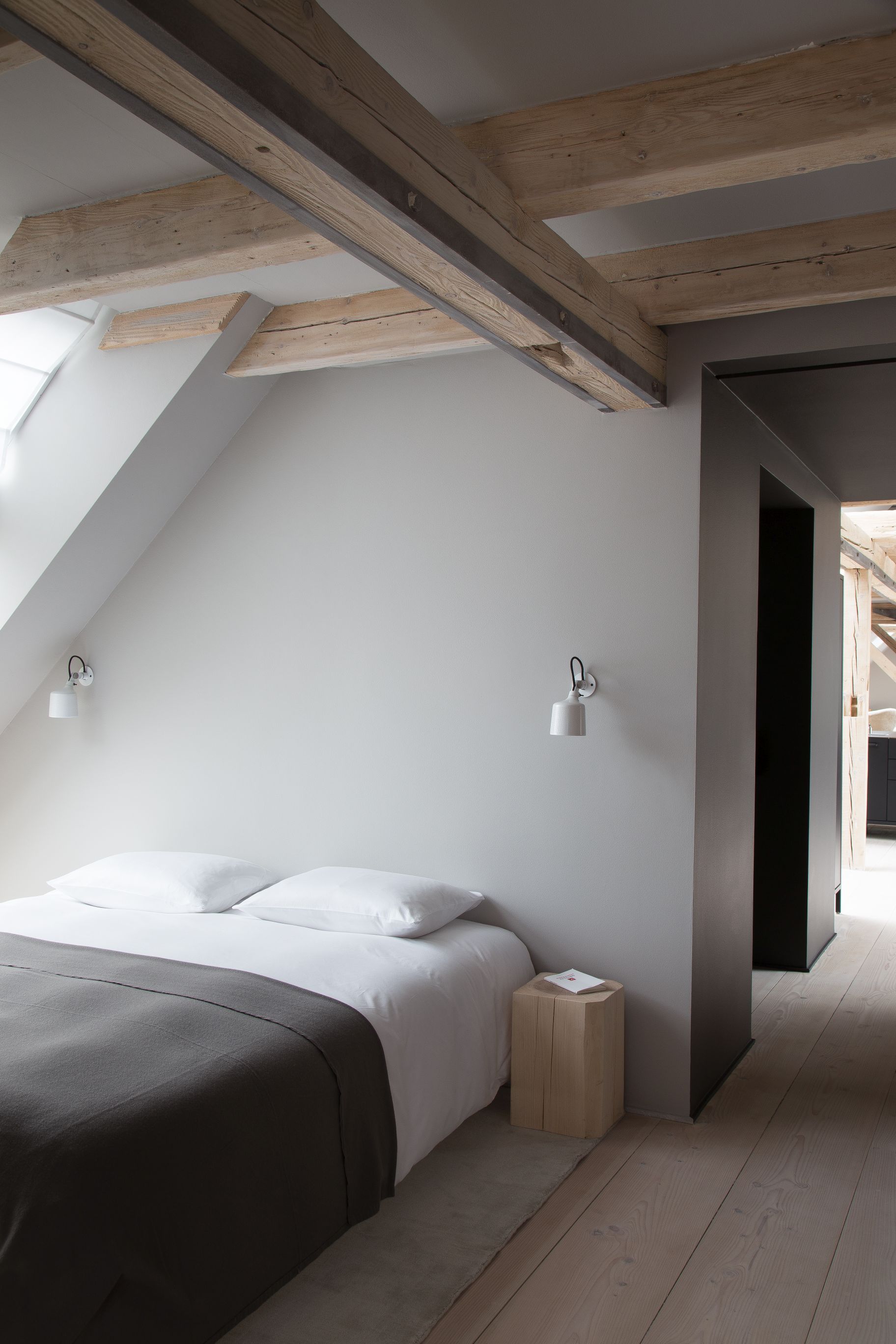 Schlafzimmer mit Bett und zwei weißen Vipp Wandspots als Beleuchtung an der Wand.