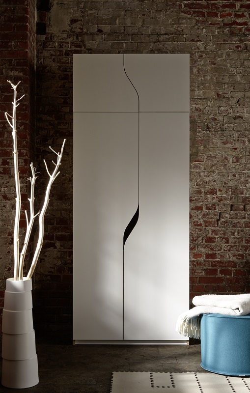 Weißer Plane Kleiderschrank von Müller Möbelwerkstätten mit minimalistischem Design vor einer Backsteinwand.