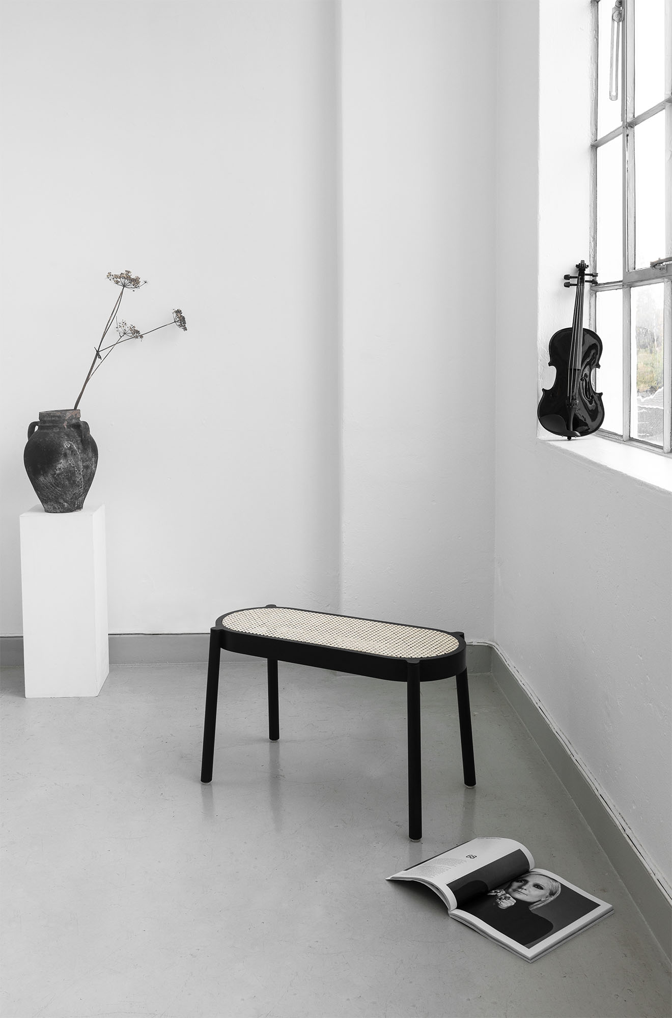 Pal Bank Northern: Schwarze Bank mit Rattan-Sitzfläche in minimalistischem Raum mit Dekoration.