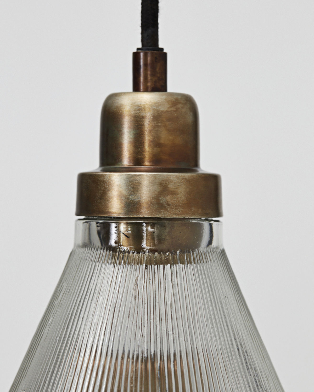 Detailaufnahme der Vira Pendelleuchte von House Doctor mit geriffeltem Glasschirm und Messingfassung.