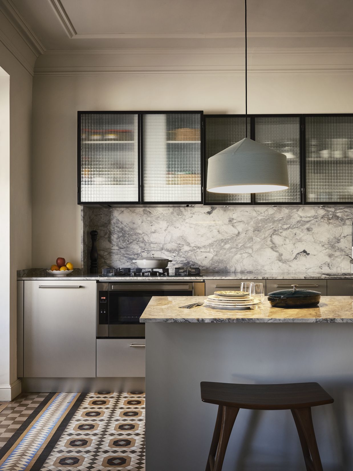 Graue Zenc Pendelleuchte von Marset hängt über einer modernen Küche mit Marmor und stilvollen Details.