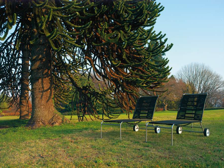 Zwei Green Sonnenliegen auf Rasen vor einem Baum, moderne Gartenmöbel mit Rollen.