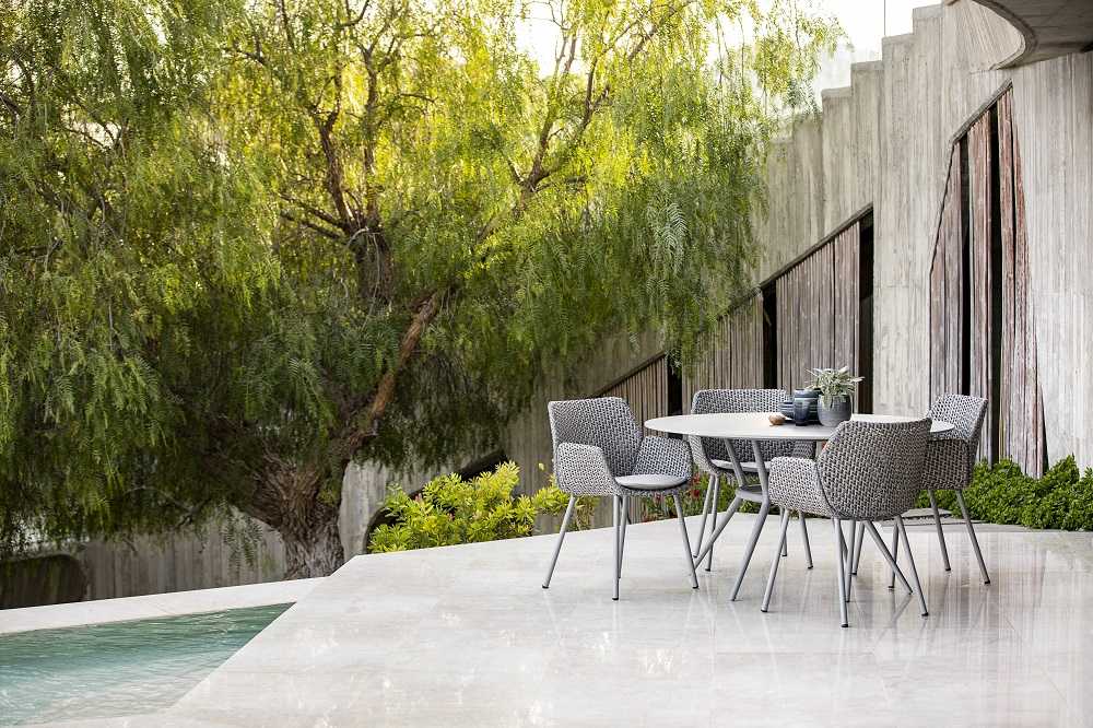 Joy Outdoor Esstisch von Cane-Line: Runder Gartentisch mit hellgrauem Gestell und Kompaktlaminat-Tischplatte.