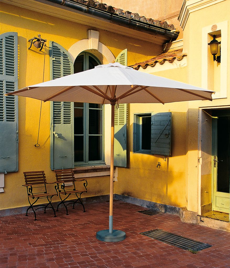 Weißer Weishäupl Sonnenschirm Ø 335 cm auf einer Terrasse mit Stühlen und gelbem Gebäude im Hintergrund.