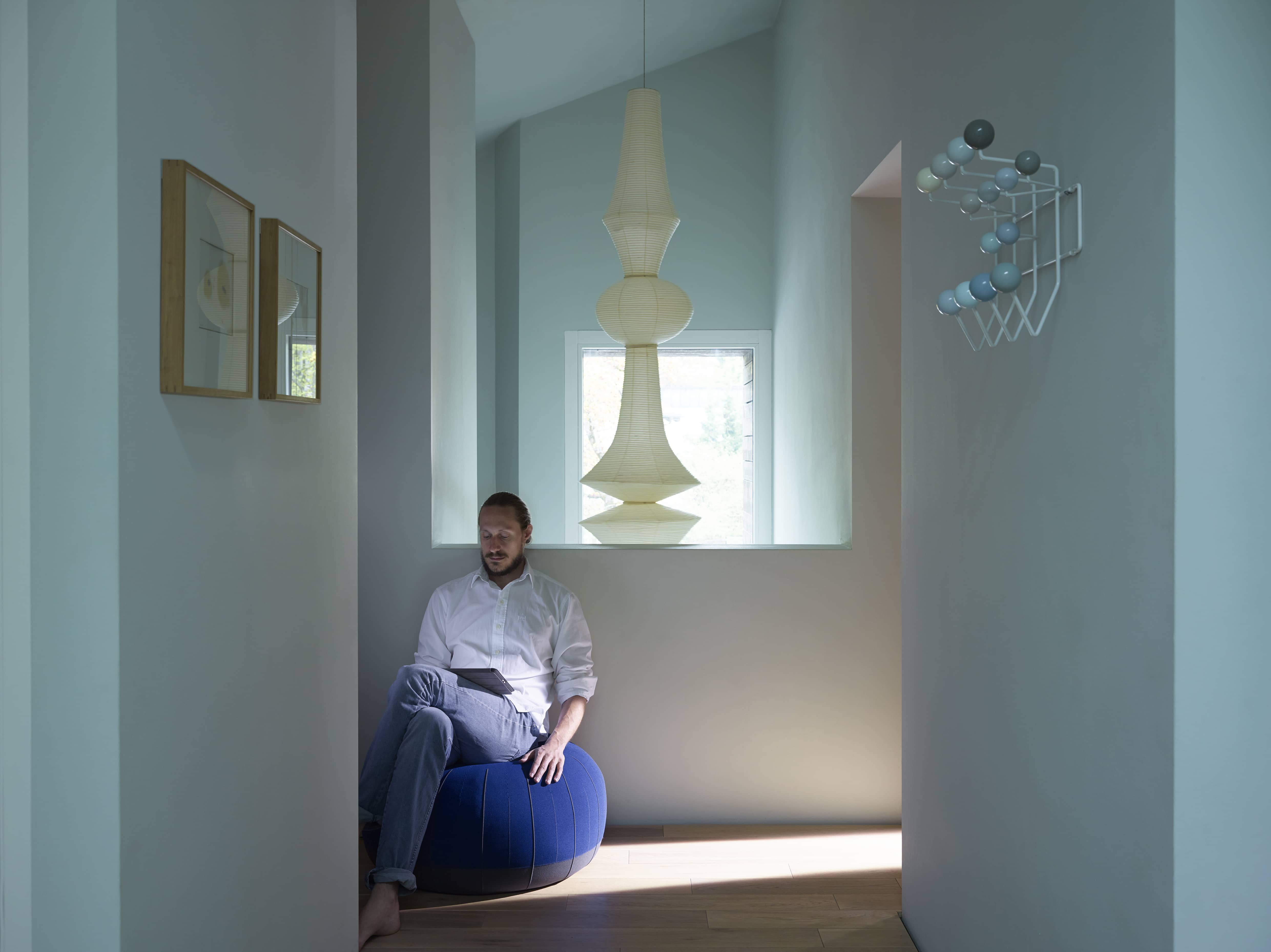 Mann sitzt unter einer Akari Hängeleuchte von Vitra, die den Raum mit sanftem Licht erfüllt.