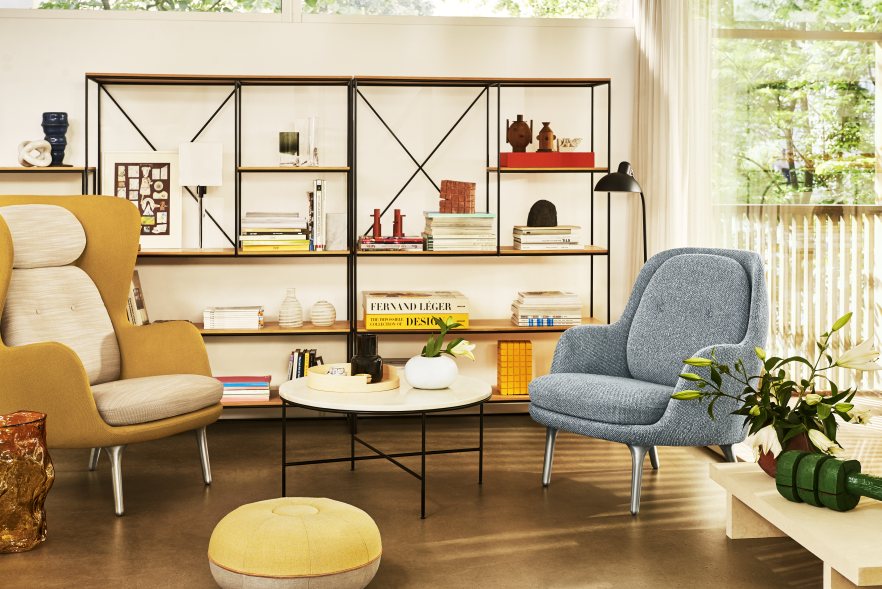 Wohnzimmer-Szene mit Fritz Hansen Pouf Hocker Large in warmem Sand und Designermöbeln.