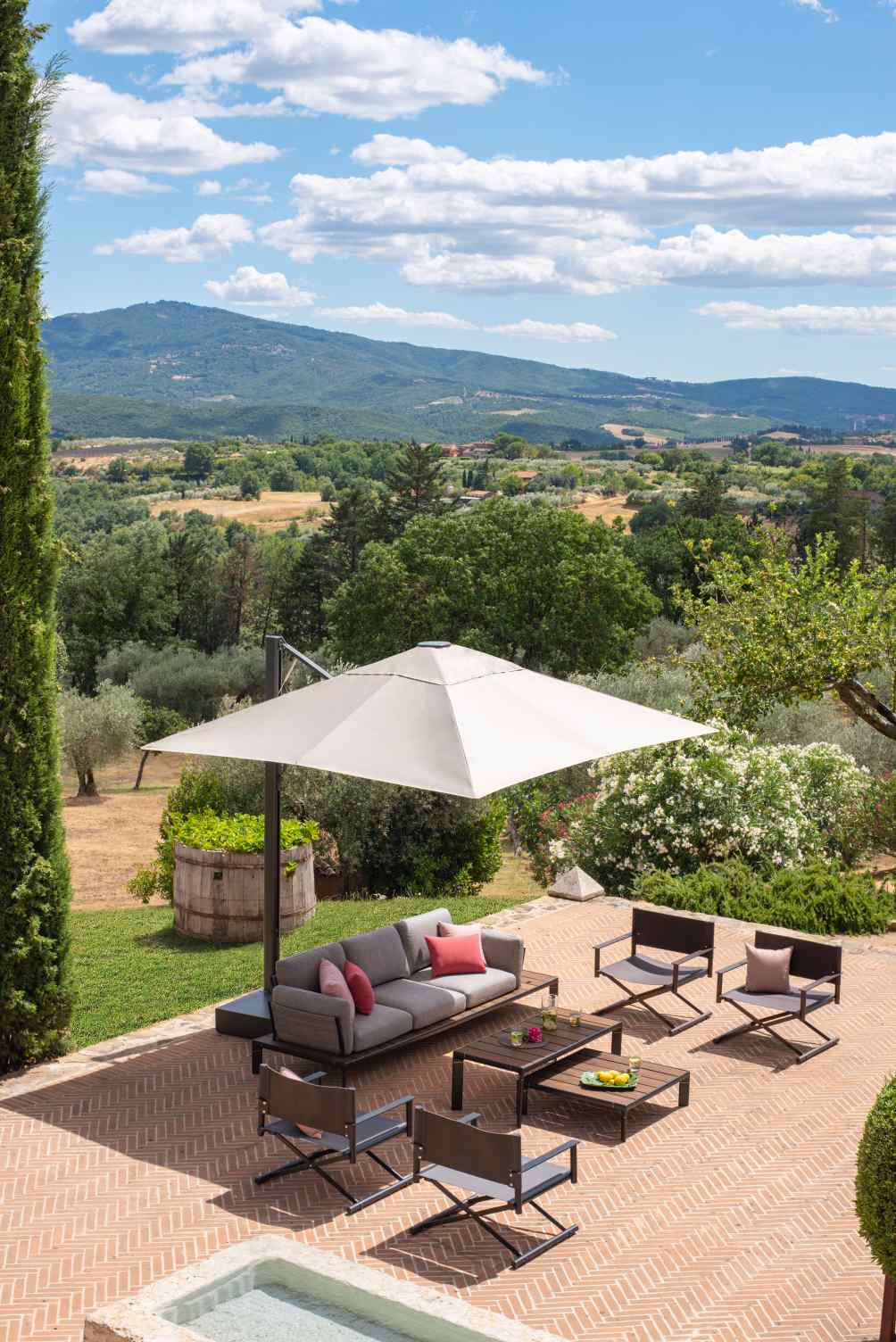 Emu Terra Lounge Chair Outdoor Sessel mit Sofa und Tisch auf einer Terrasse mit Landschaft.