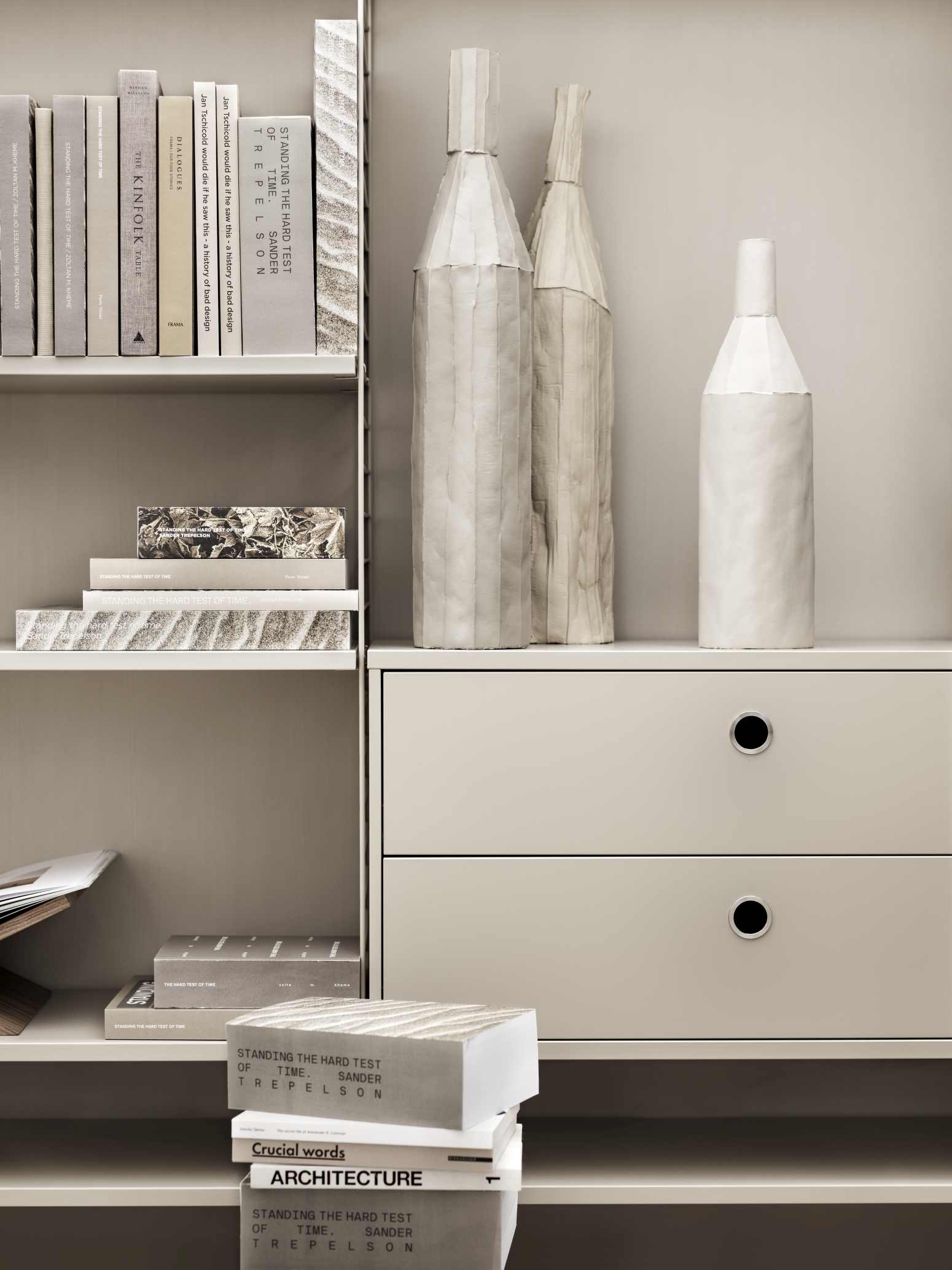 Detailaufnahme eines String Regalsystems mit Schubladen, Büchern und dekorativen Vasen.