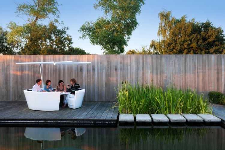 Kosmos Outdoor Sitzgruppe: Vier Personen sitzen entspannt am Tisch mit Sonnenschirm.