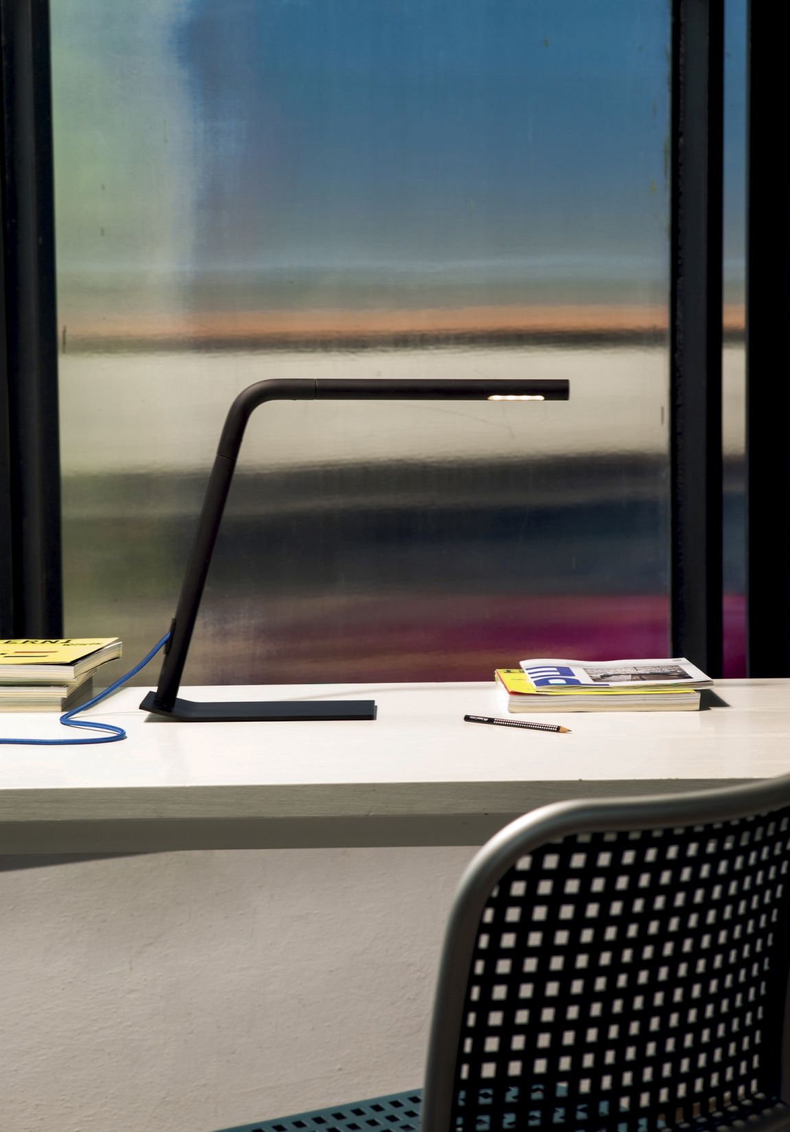 Schwarze Colibrì Tischleuchte von Martinelli Luce auf einem Schreibtisch mit Büchern und Stift.