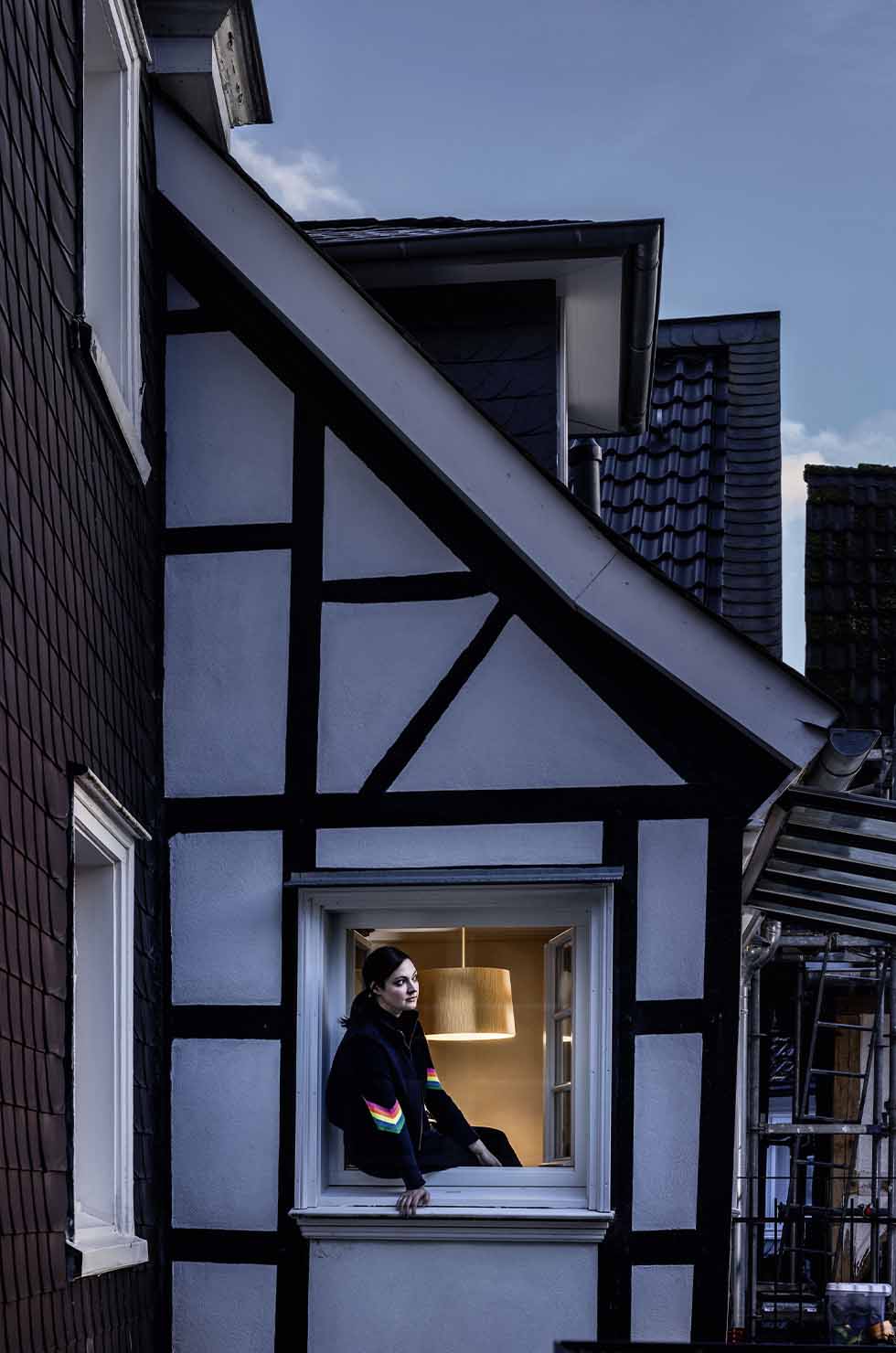 Frau sitzt im Fenster, beleuchtet durch die Foscarini Twiggy Pendelleuchte, modernes Lampendesign für Wohnräume.