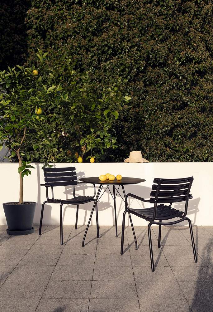 Zwei schwarze ReClips Outdoor Dining Stühle von Houe mit Tisch auf einer Terrasse.