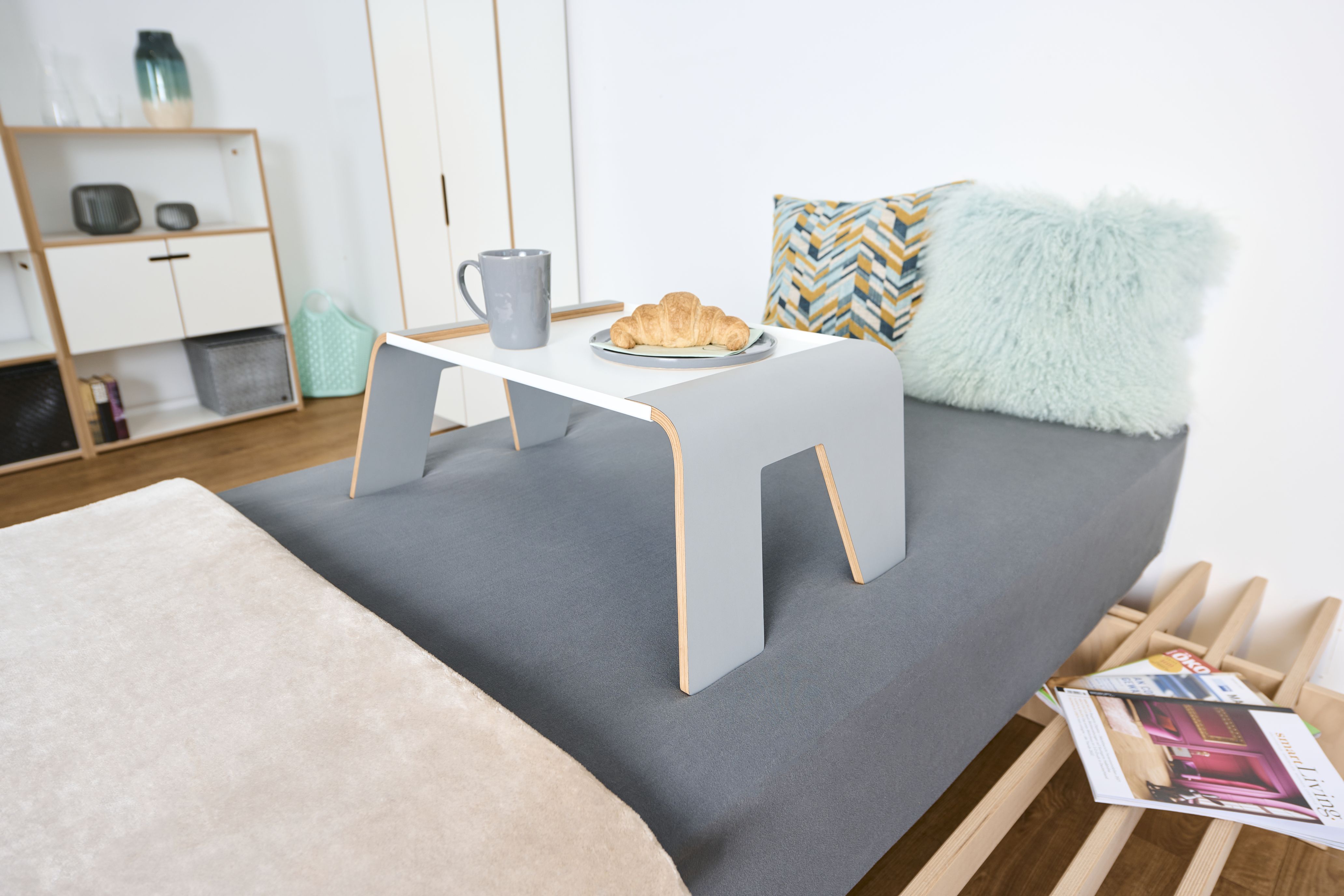 Tojo Tablett auf Bett mit Tasse und Croissant. Praktischer Notebooktisch für Bett und Sofa.