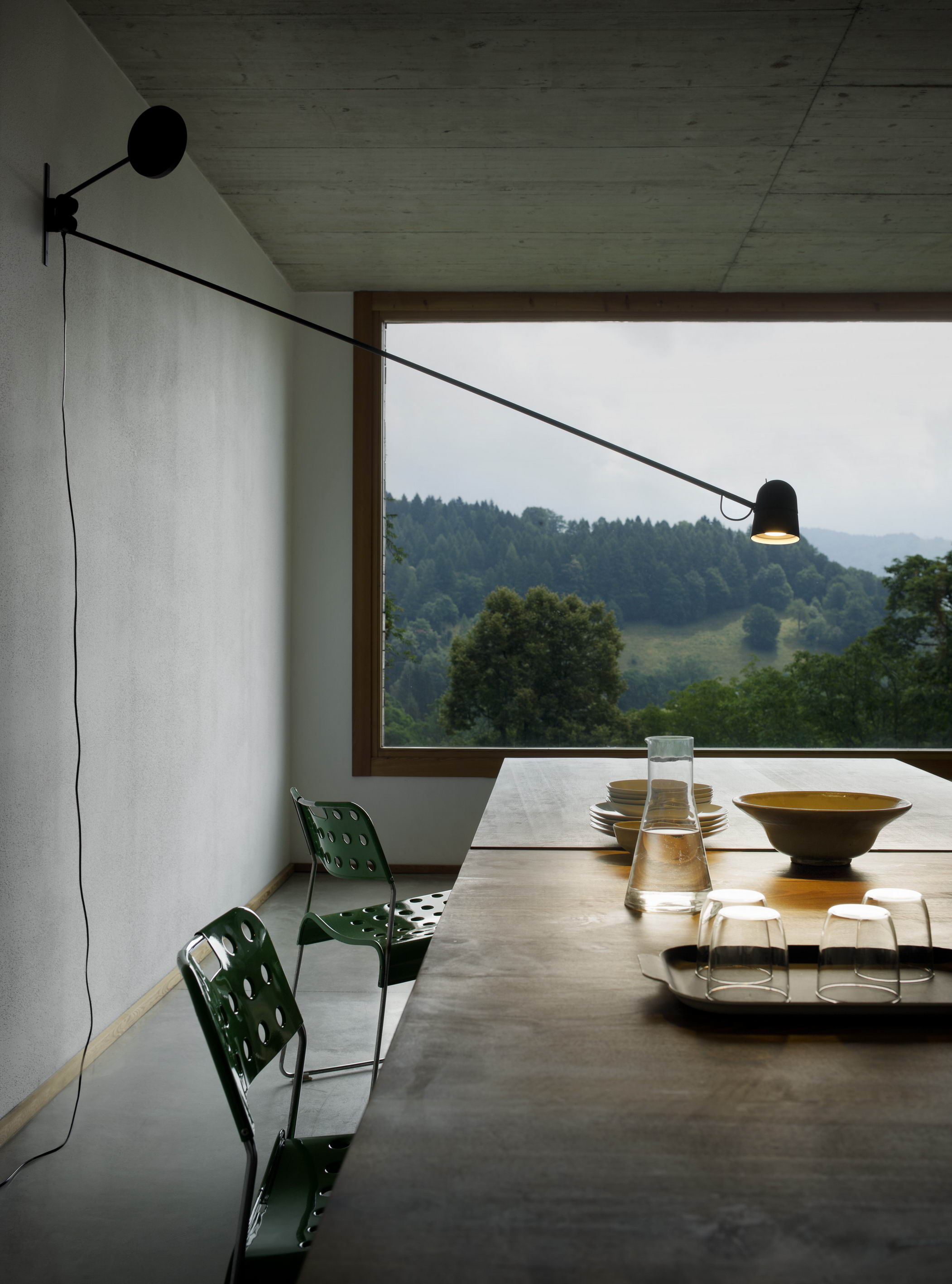 D73N Counterbalance Wandleuchte von Luceplan über Esstisch mit Geschirr und Blick in die Natur.