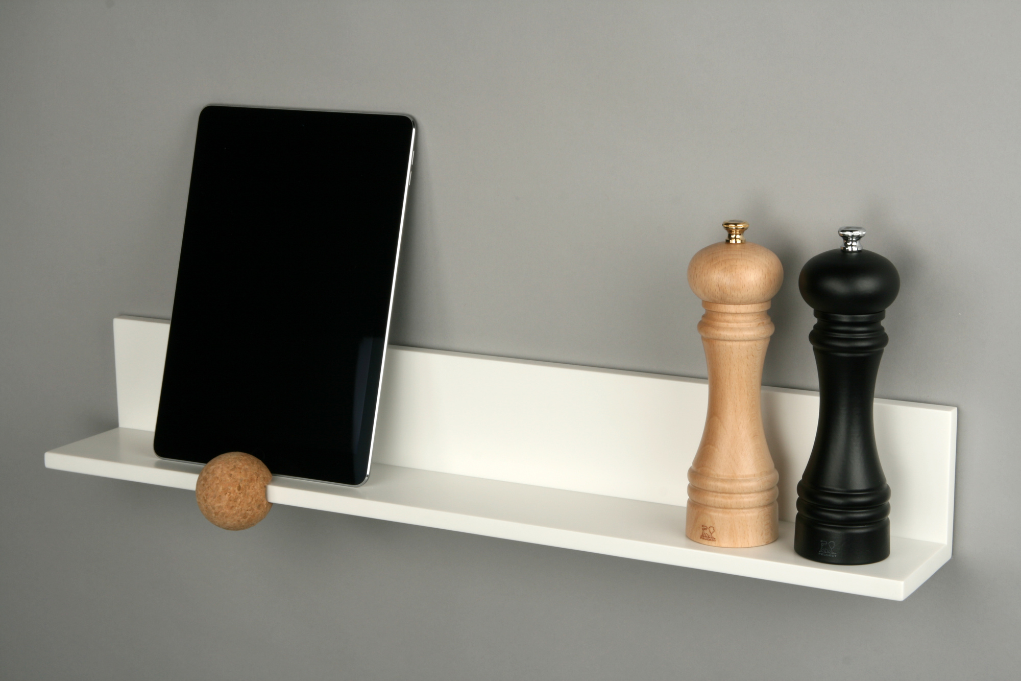 Weißes Wandboard mit Tablet, Korkkugel und Pfeffermühlen. Straights Wandregal für moderne Wandgestaltung.