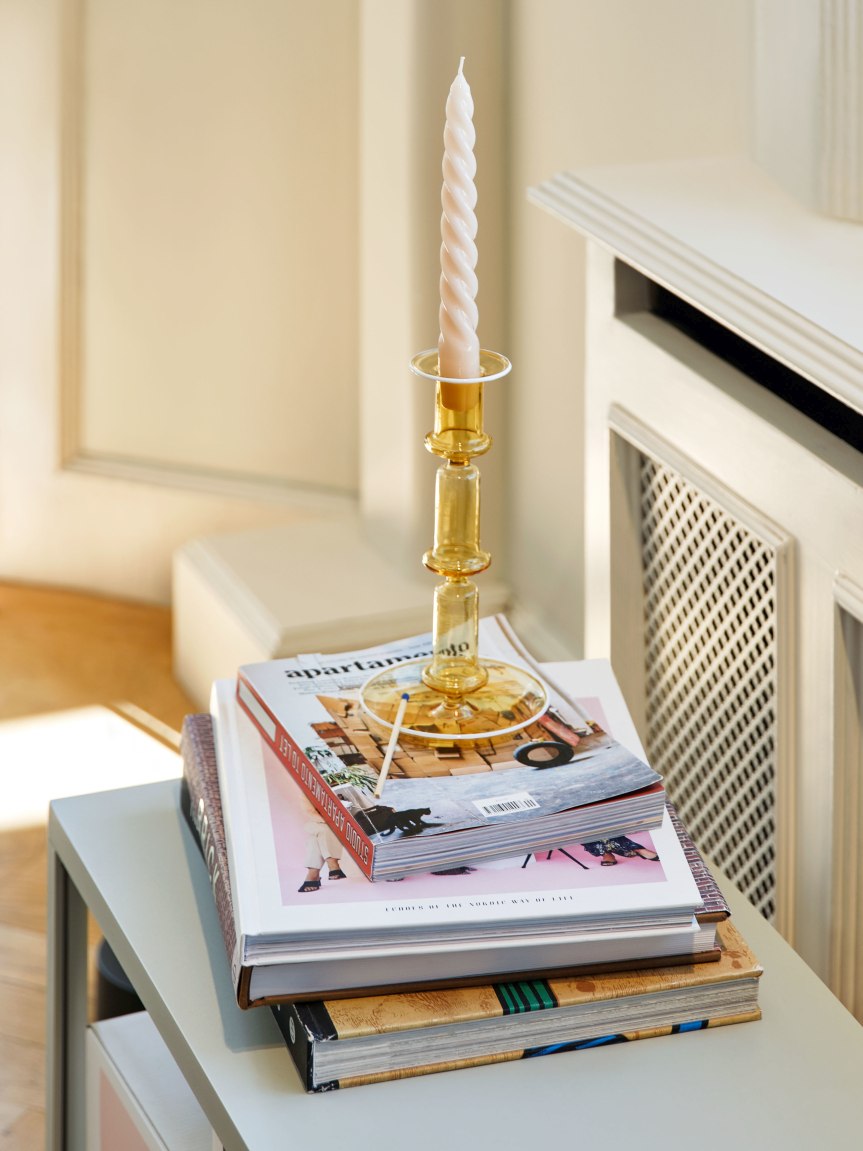 Gelber Flare Kerzenständer von Hay auf Bücherstapel mit gedrehter Kerze. Dekorative Wohnaccessoires für stimmungsvolles Licht.