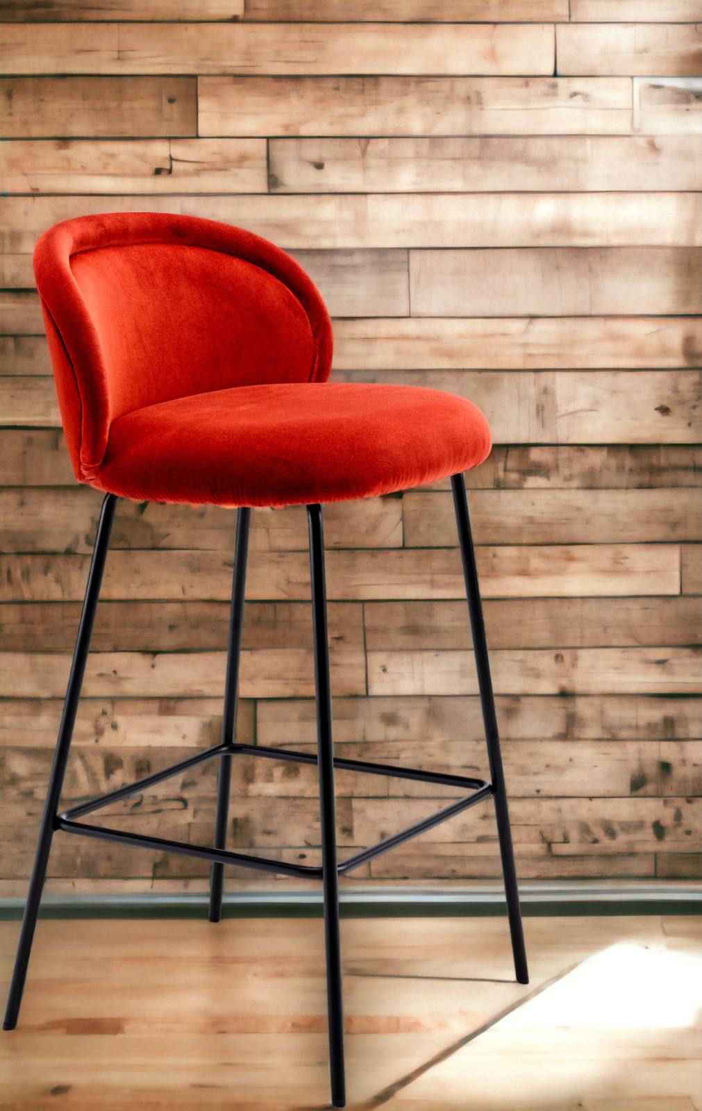 Roter Ona Barhocker von Freifrau Manufaktur mit schwarzem Gestell vor Holzwand. Moderner Tresenhocker.