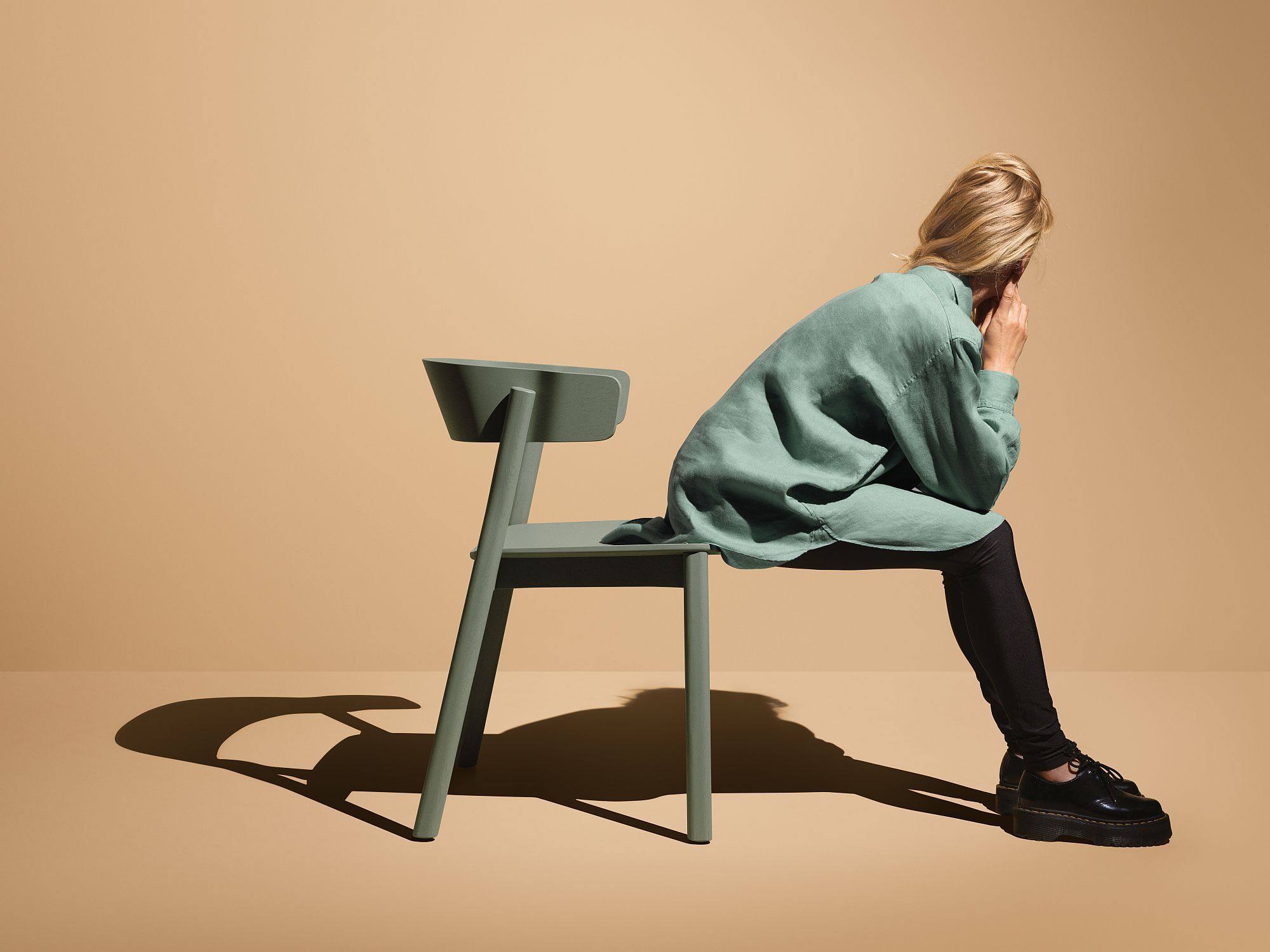 Frau sitzt auf grünem Enfold Chair Stuhl von Mizetto, modernes Möbeldesign für Wohnen und Büro.