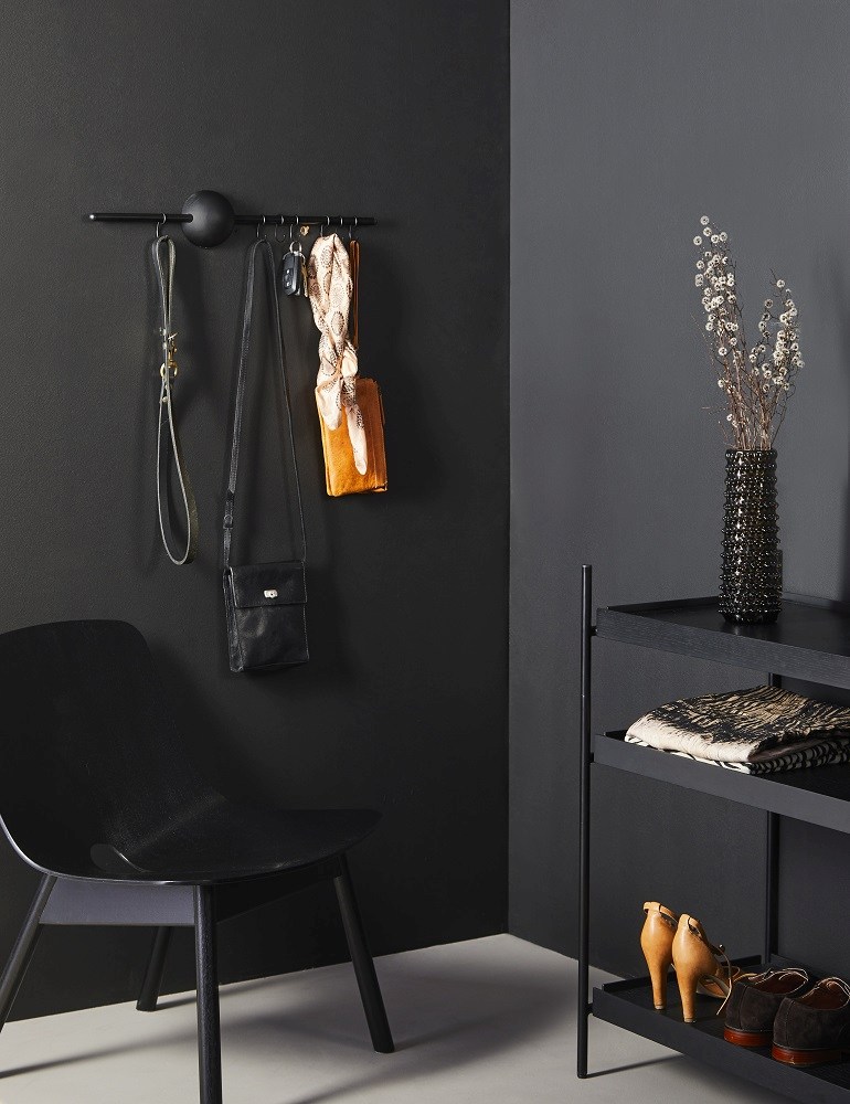 Schwarze Hoop Rack Wandgarderobe von Woud mit Accessoires an einer dunklen Wand. Design Garderobe.