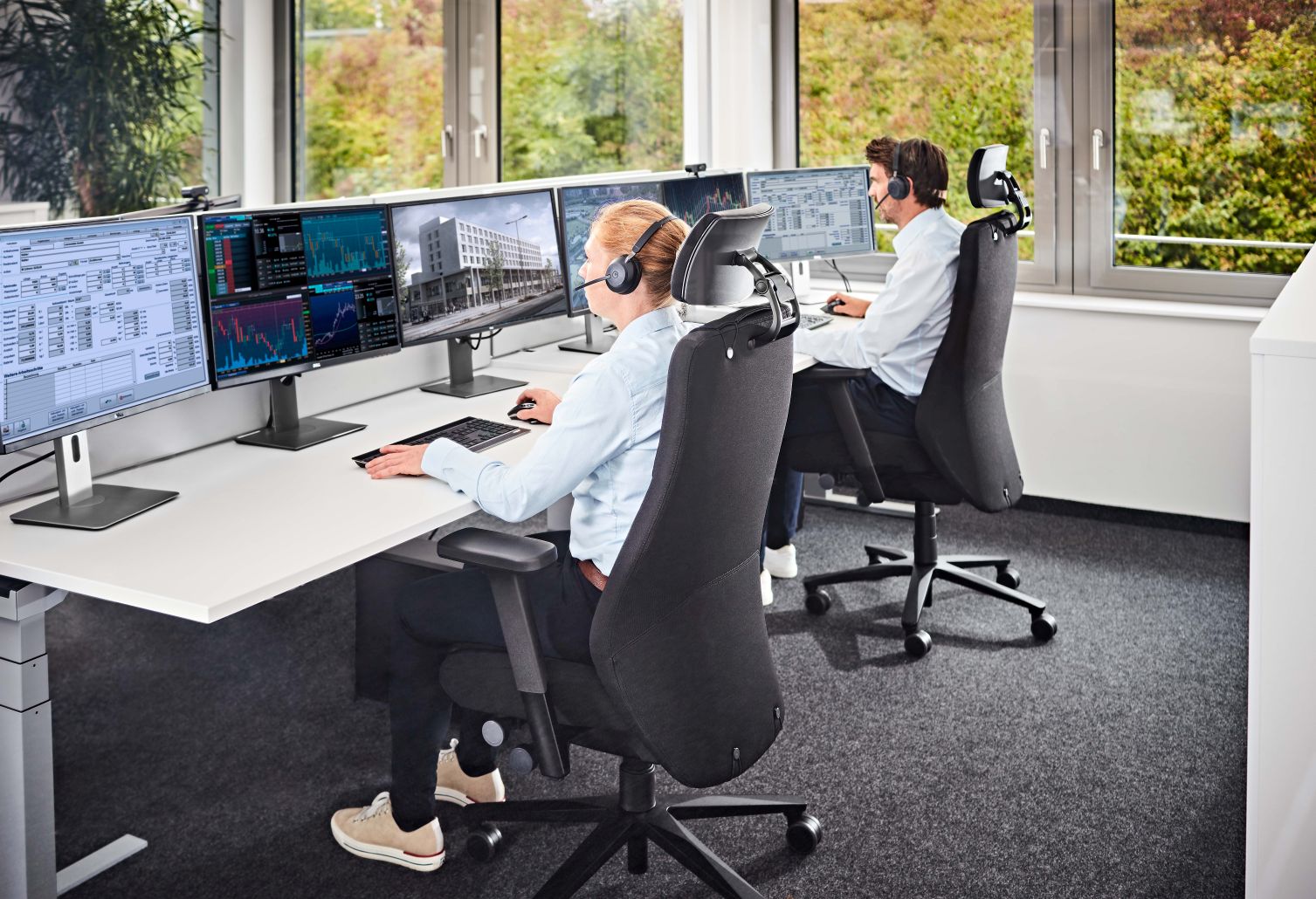 Twentyfour is5 Bürostuhl: Zwei Personen sitzen an Schreibtischen mit mehreren Monitoren in ergonomischen Drehstühlen.