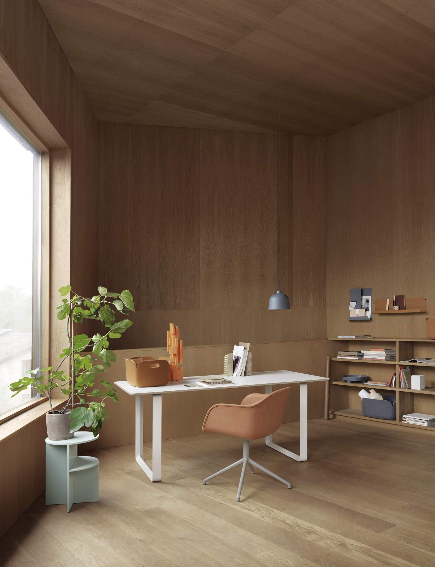 Büro mit Muuto Folded Shelves Regal, Schreibtisch, Stuhl und Dekoration in einem Holzraum.