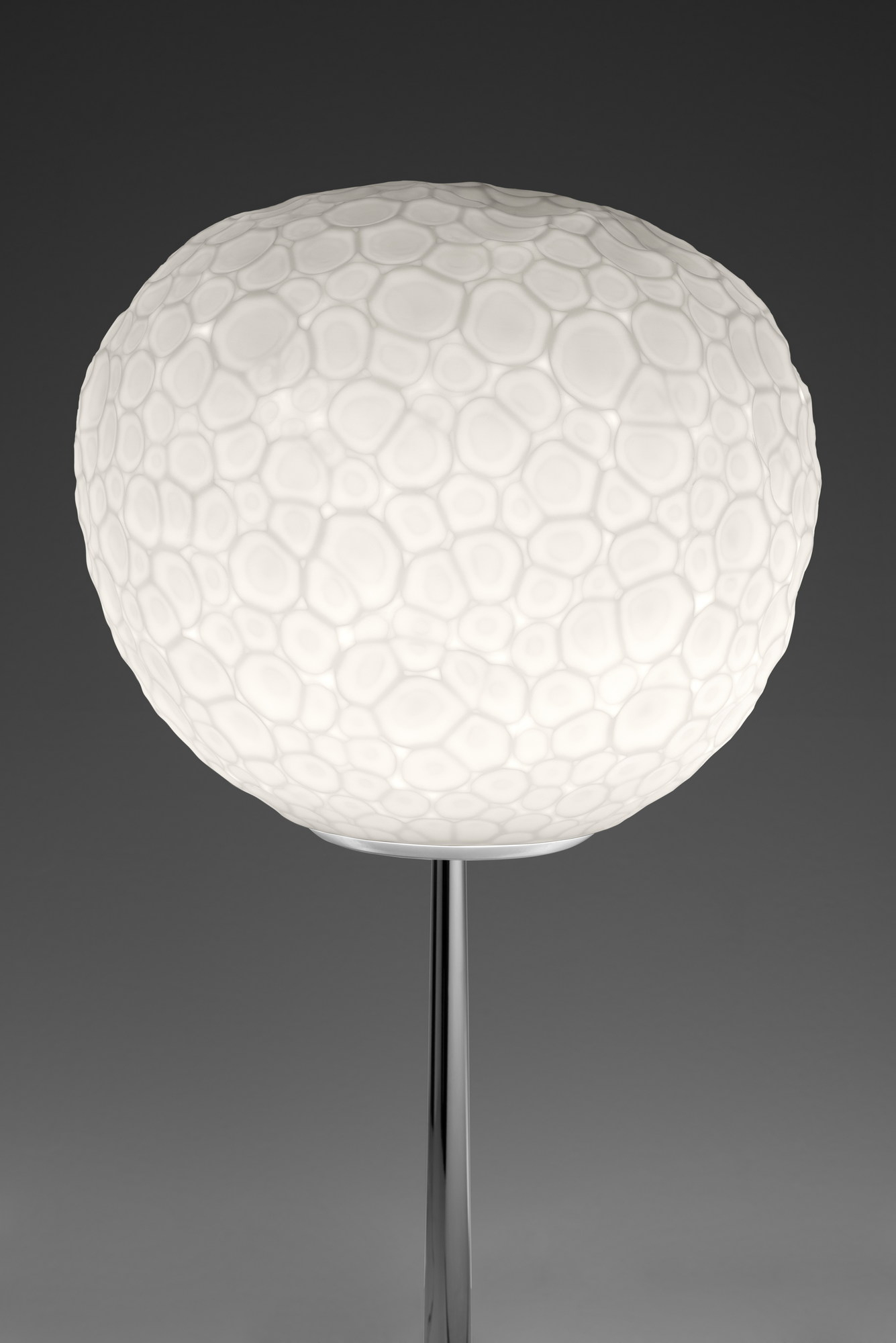 Meteorite Tischleuchte von Artemide: Runde, weiße Designerlampe mit Struktur auf einem schlanken, silbernen Fuß.