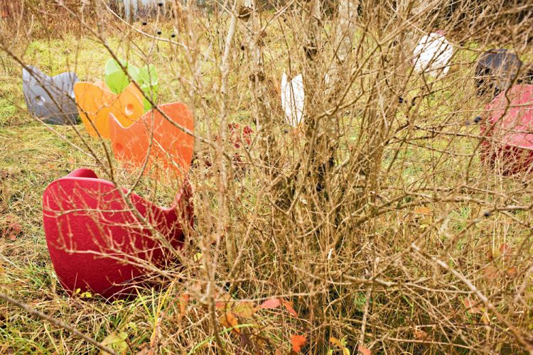 Roter O-Nest Sessel von Moroso im Garten, teilweise von Ästen und Pflanzen verdeckt.