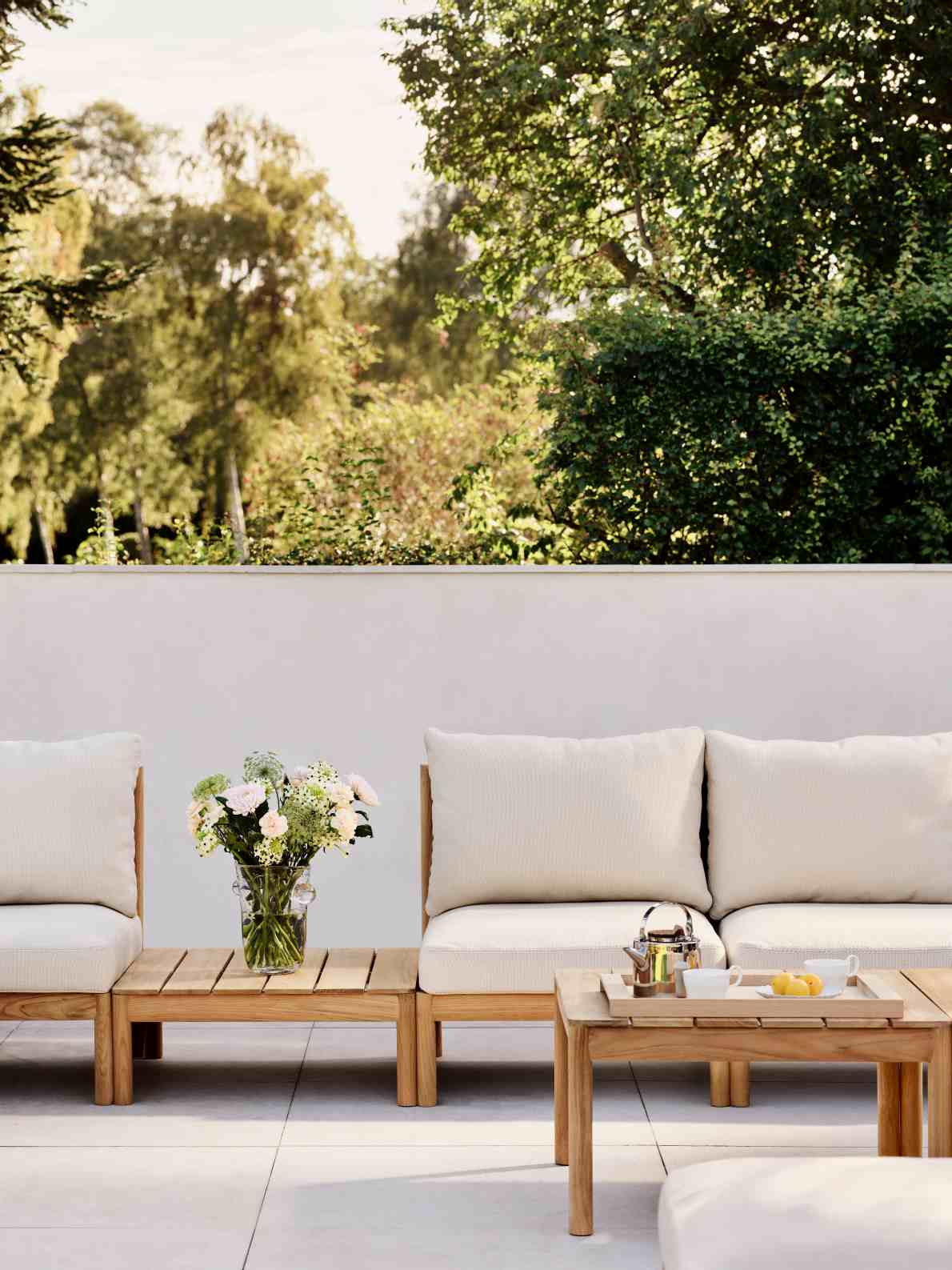 Tradition Lounge Tisch von Skagerak by Fritz Hansen aus Teakholz mit Blumen und Teegeschirr im Garten.