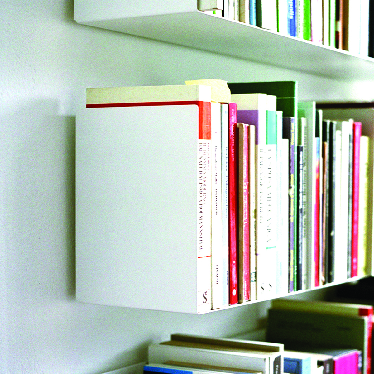 Weißes Wandregal a Linea1 von Müller Möbelwerkstätten mit Büchern, modernes Bücherregal für Wohnzimmer und Büro.