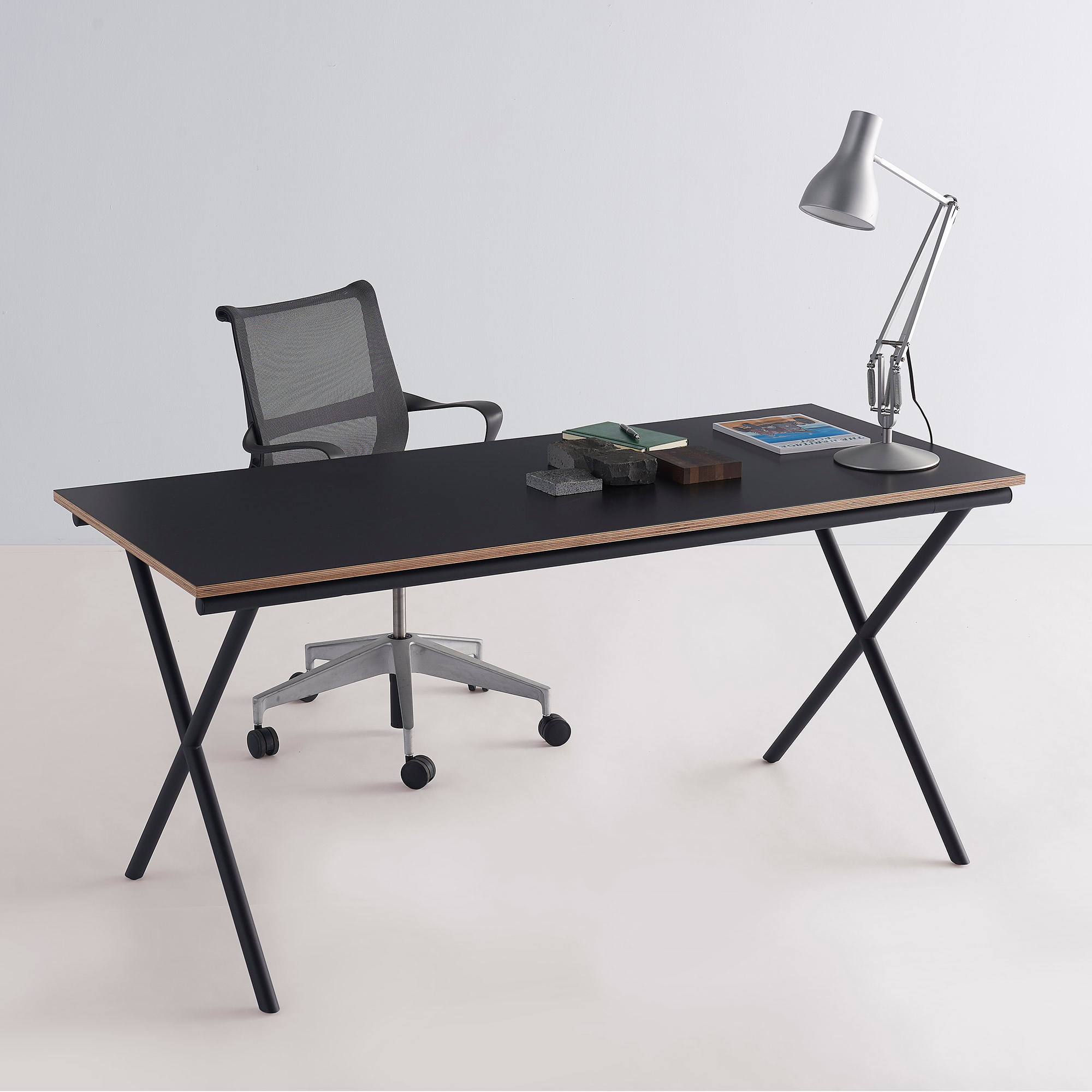 Schwarzer Ito Arbeitstisch mit X-förmigem Gestell, Bürostuhl und Lampe. Moderner Schreibtisch für Büro und Homeoffice.