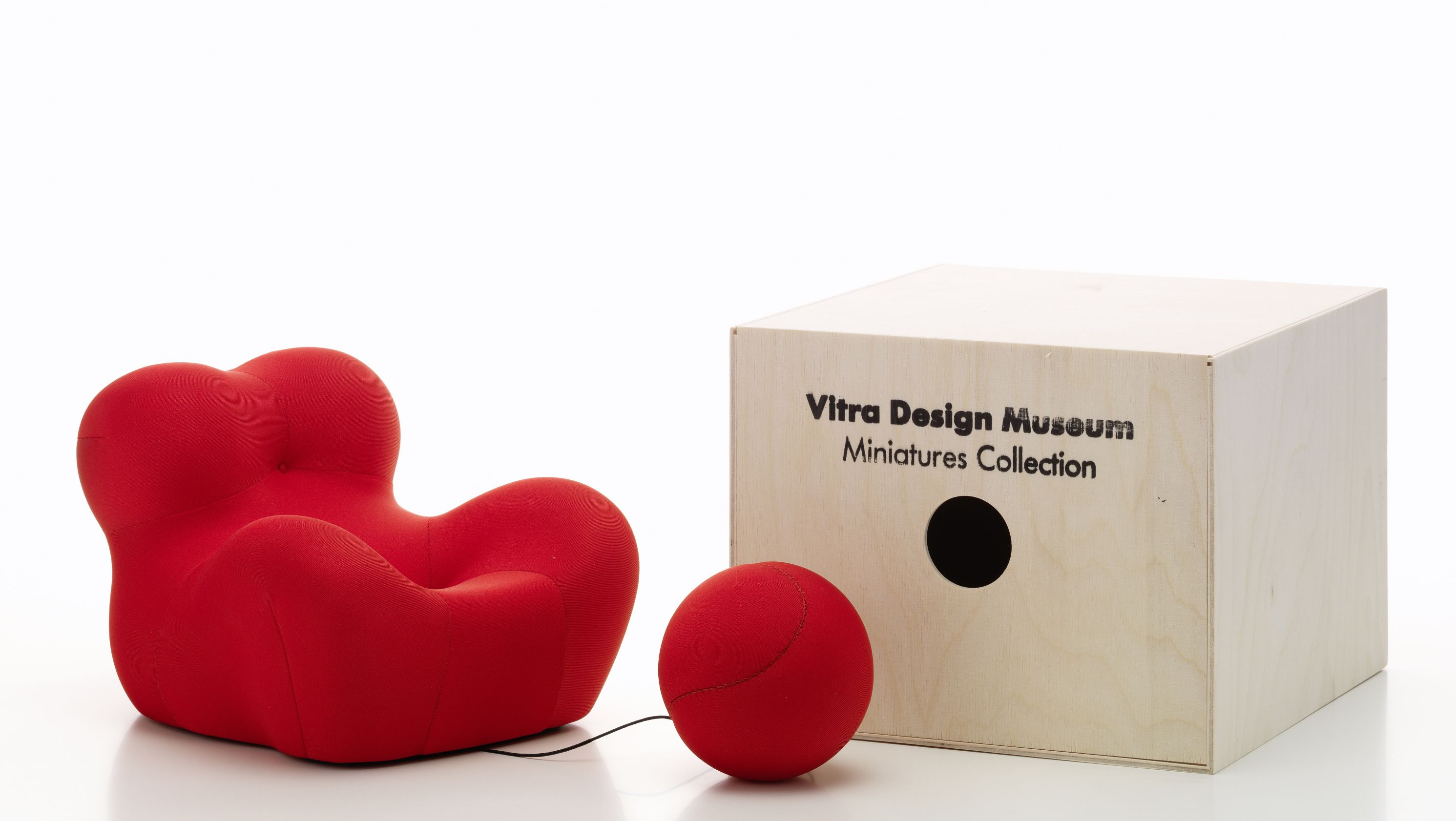 Roter La Mamma Sessel Miniatur von Vitra mit passendem Hocker und Holzkiste.