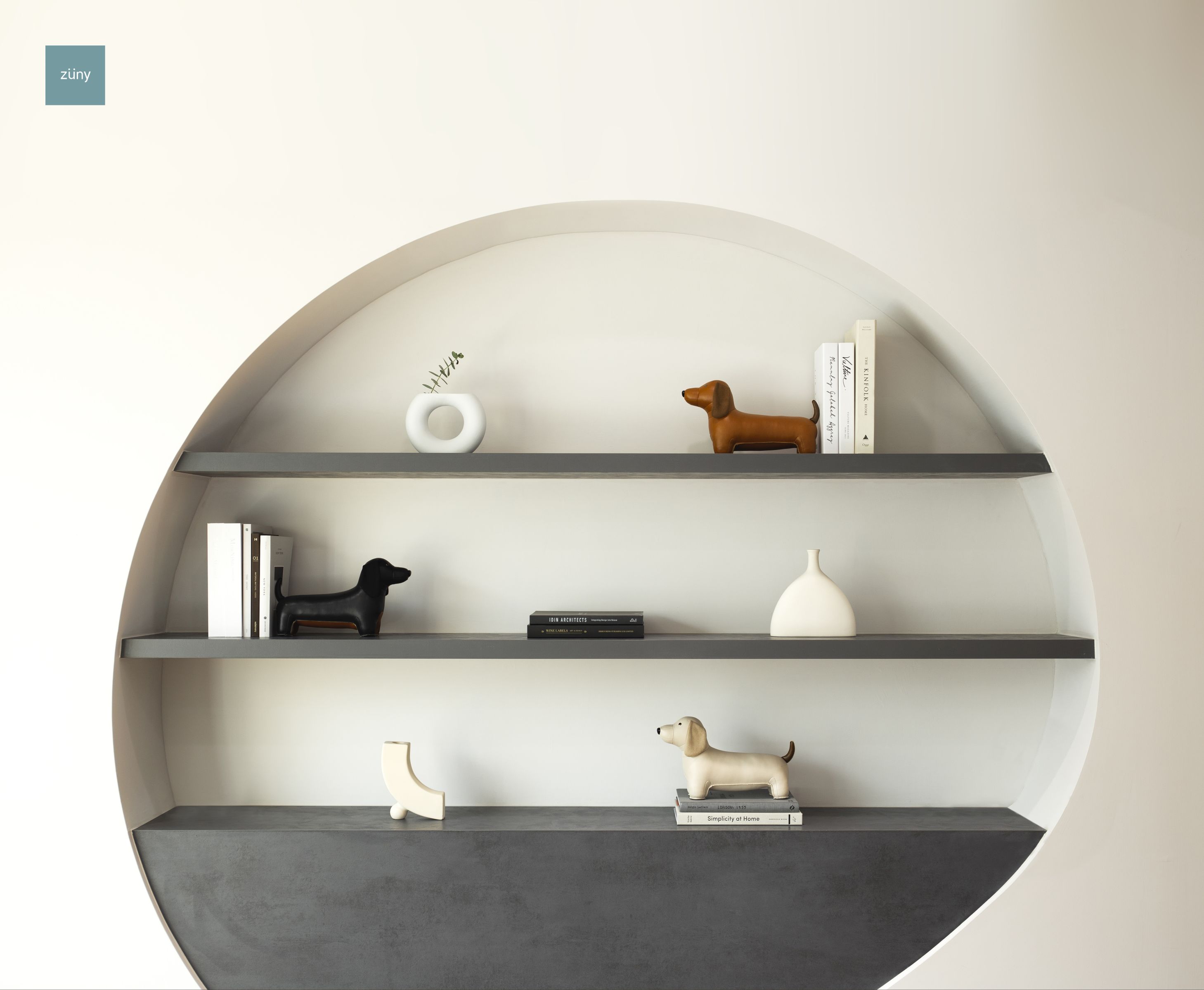 Regal mit Deko-Objekten, darunter eine weizenfarbene Dackel Buchstütze von Züny. Dekorative Wohnaccessoires für Bücher.