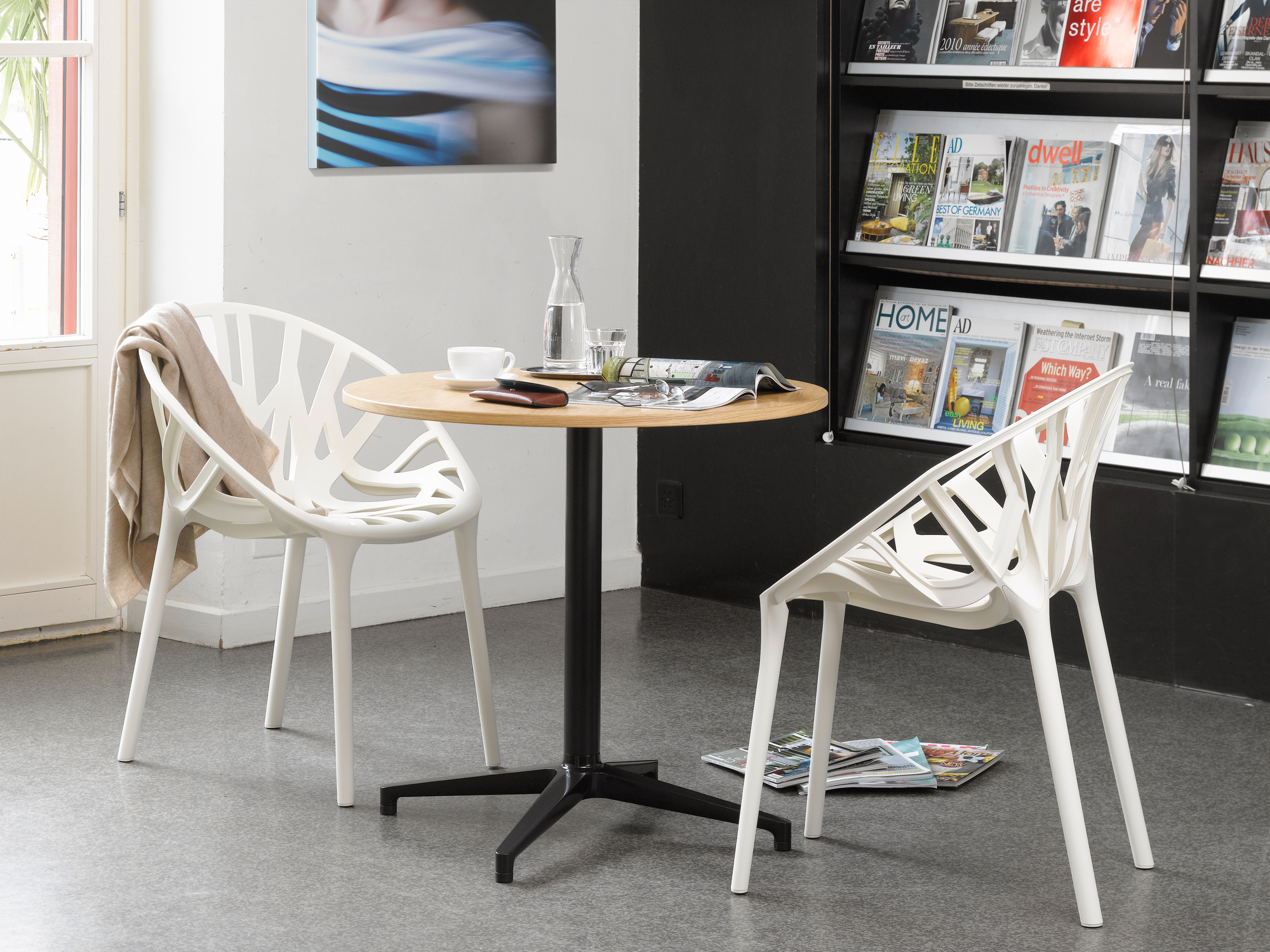 Runder Bistro Table Tisch von Vitra mit zwei weißen Stühlen im Innenbereich.