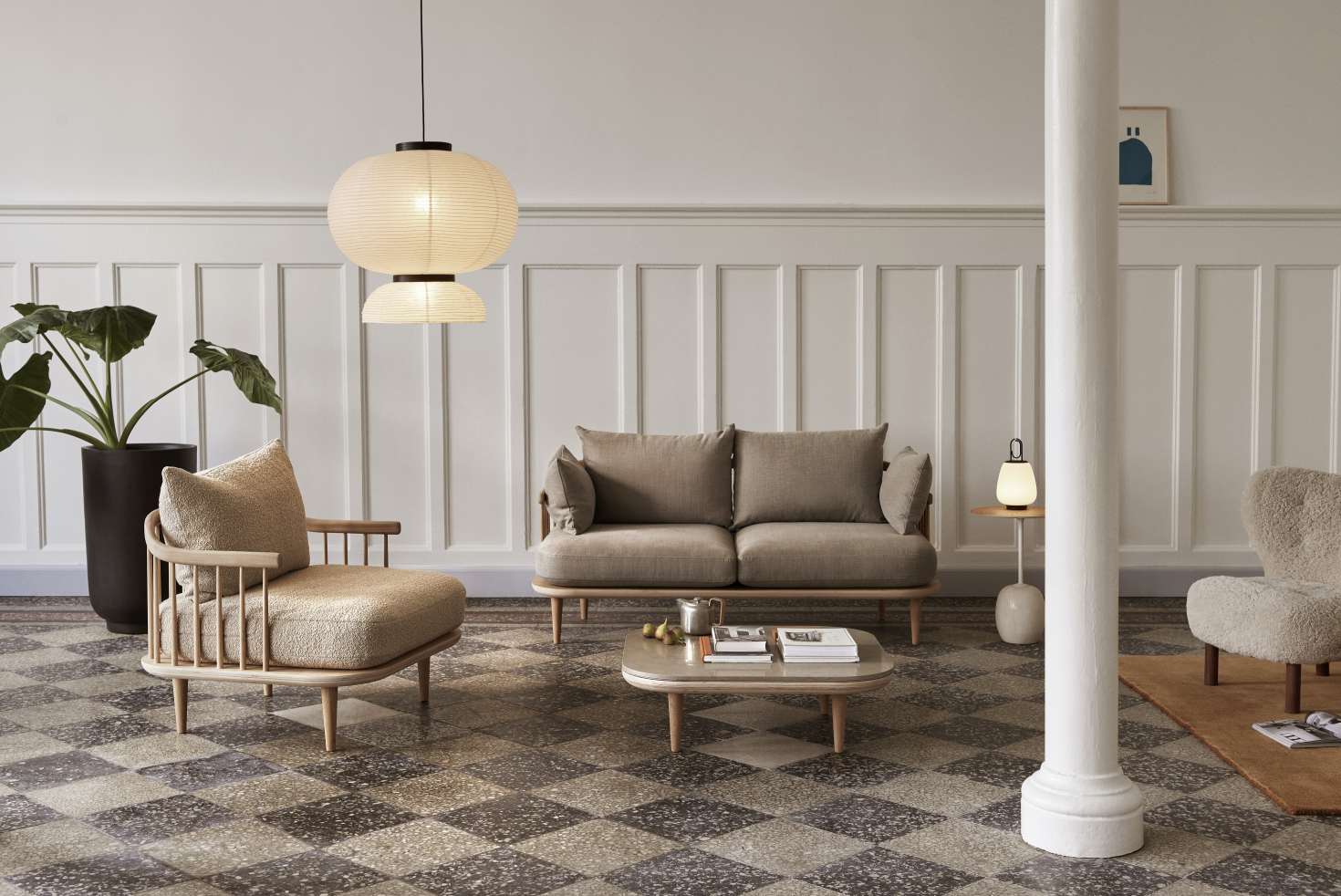 Wohnzimmer mit AndTradition Fly Couchtisch, Sofa und Sessel in Beige- und Naturtönen.