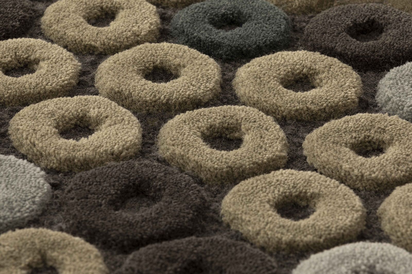 Detailaufnahme des Chimos Rug Teppichs Gan mit reliefartigen, runden Mustern in Beige-, Grau- und Brauntönen.