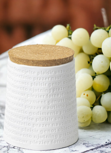 Raumpoesie Vorratsdose mit Korkdeckel, weiße Keramikdose mit "Genuss" Schriftzug, neben grünen Trauben.