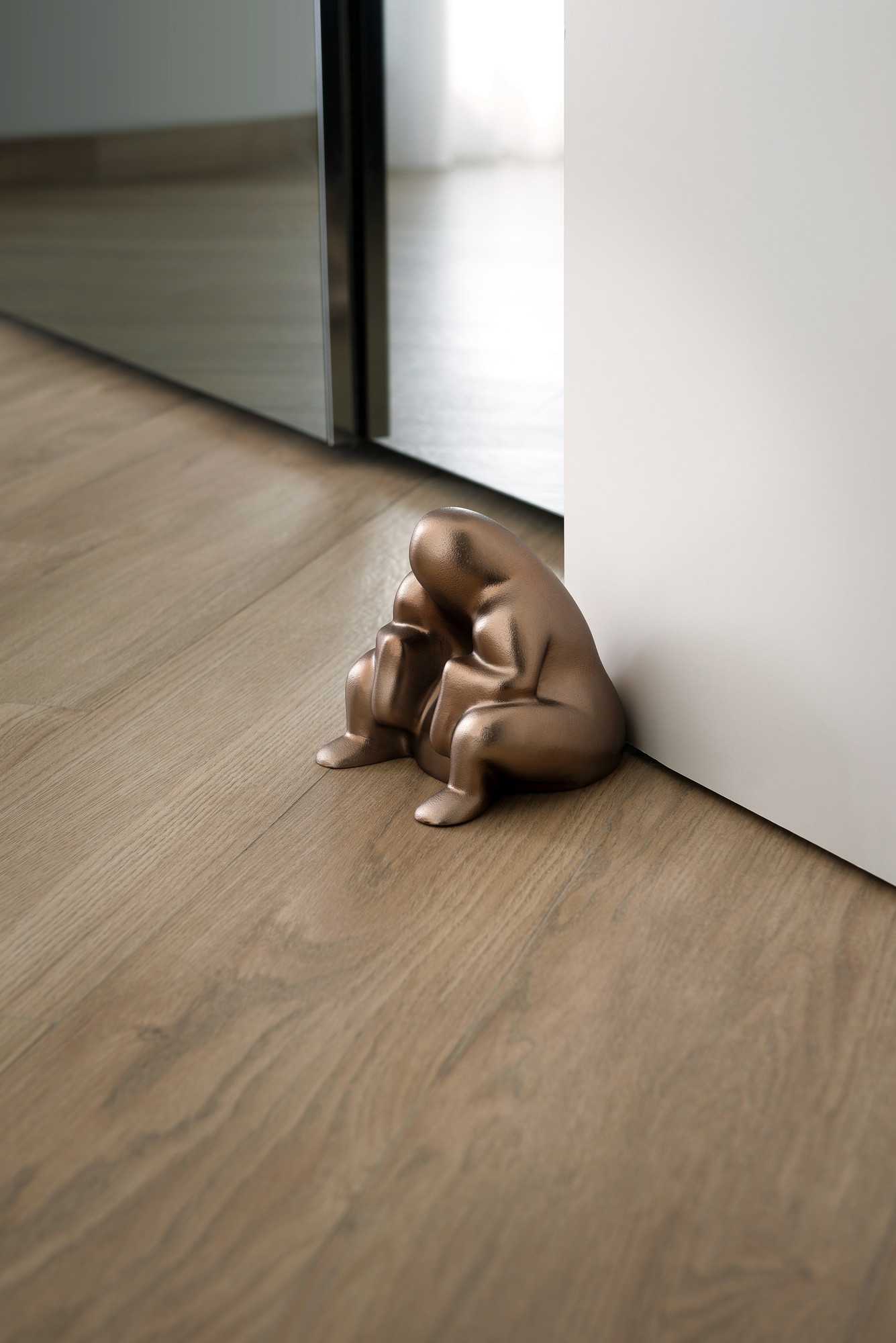 Brauner Alessi Dede Türstopper aus Metall, skulpturales Design, hält Tür auf Holzboden offen.