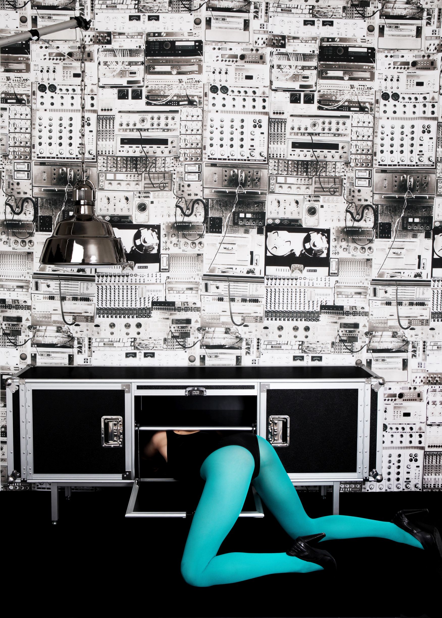 Total Sideboard schwarz von Moroso Diesel mit Person in türkiser Strumpfhose, die in das Möbelstück kriecht.