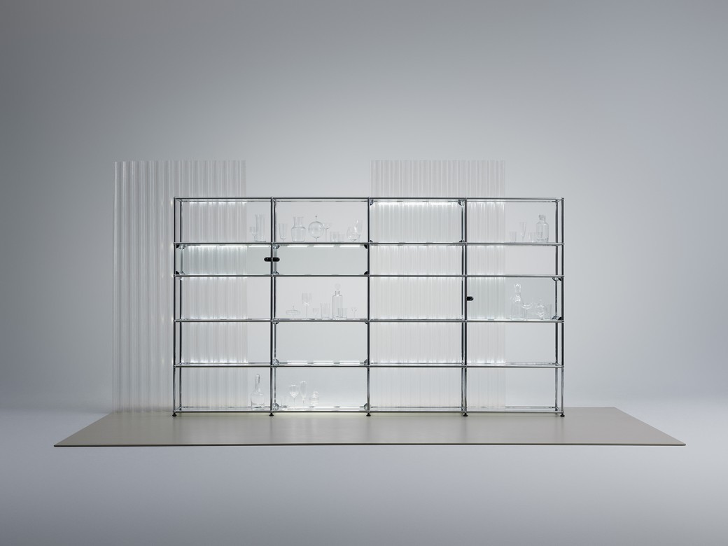 USM Haller E Regal mit integrierter, dimmbarer Beleuchtung, Glasböden und Chromgestell im minimalistischen Design.